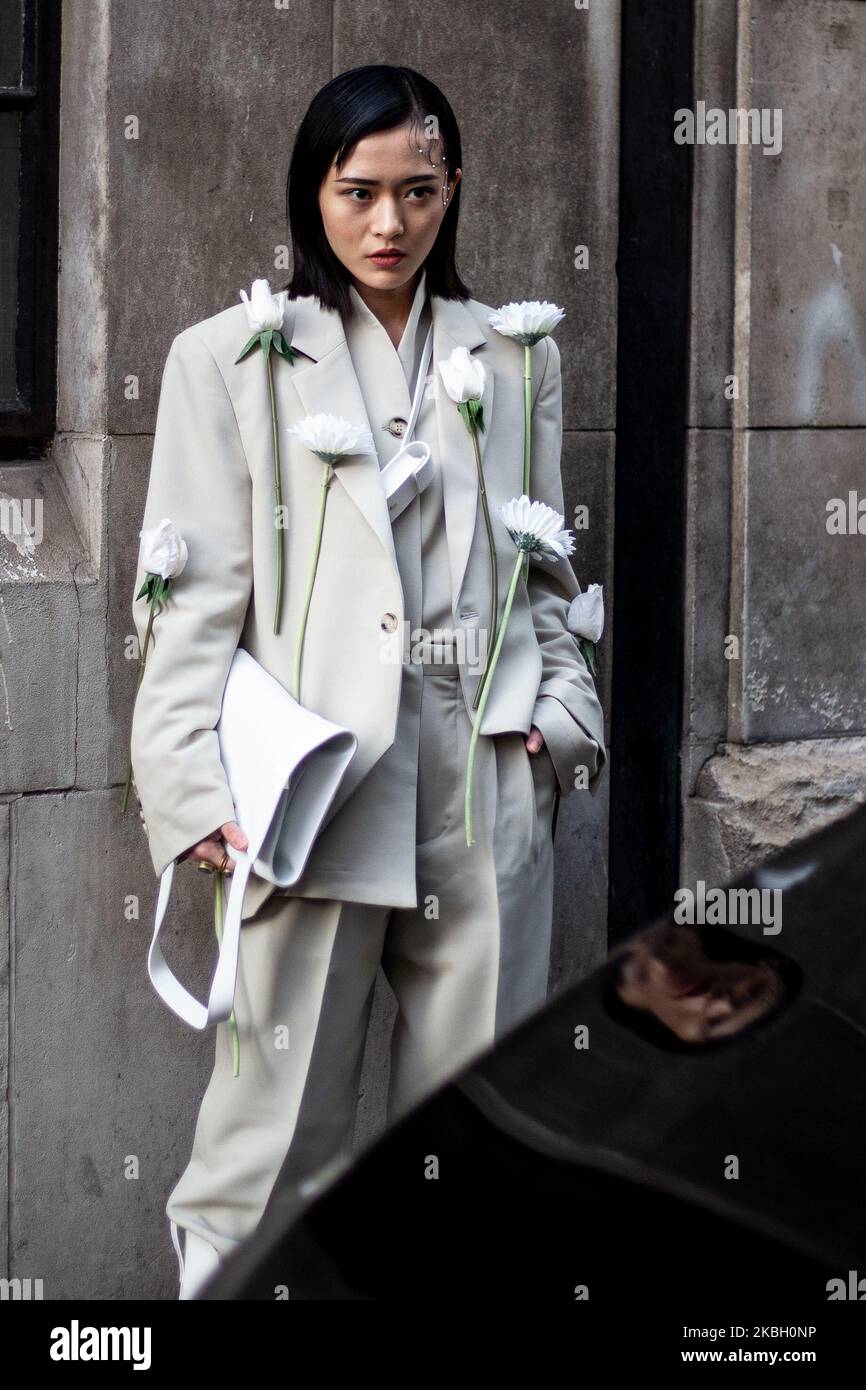 A guest wears a cream jacket with flowers attached during London