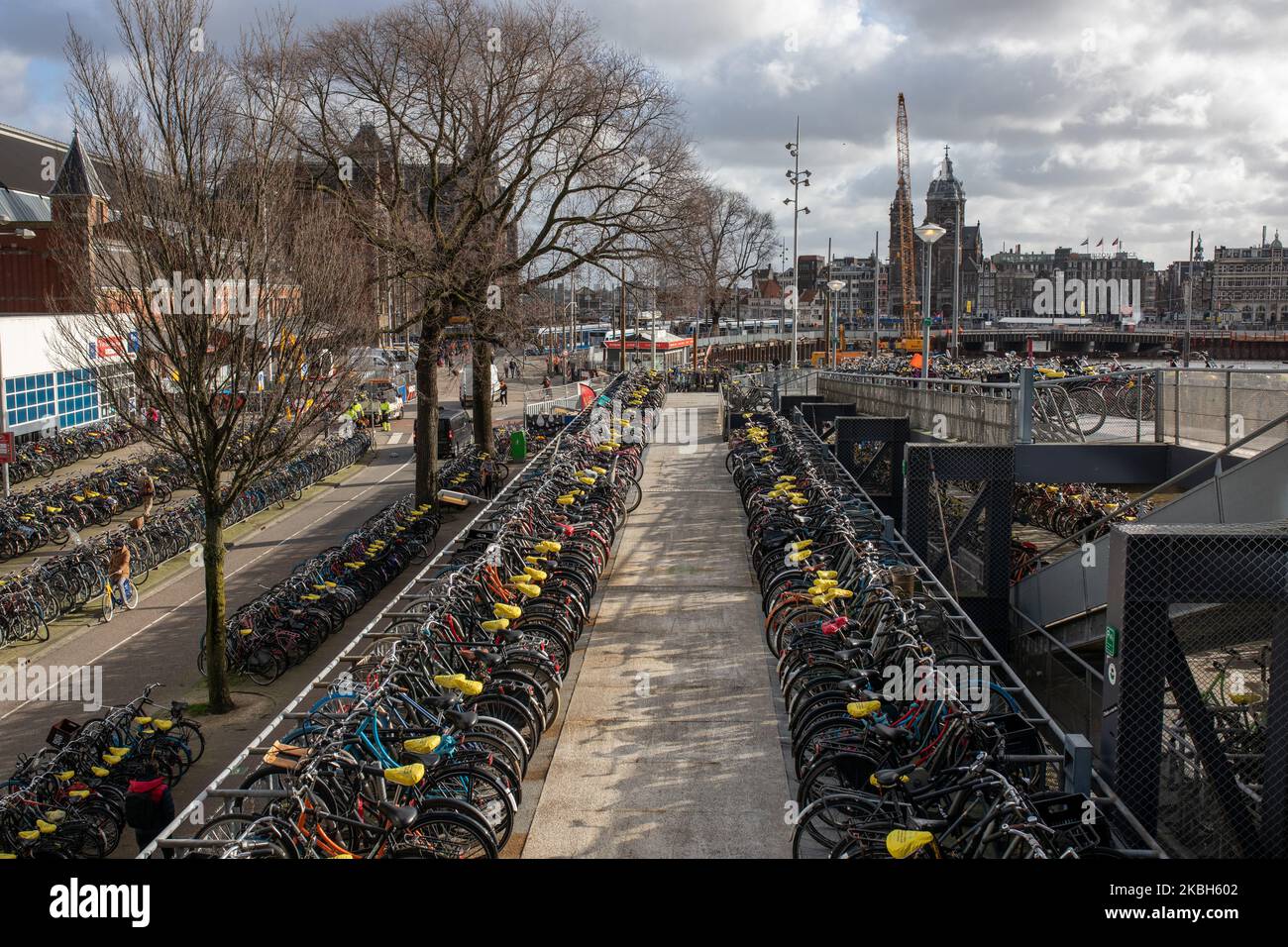 People using bikes in the city and/or electric car charging stations in Amsterdam seen on February 17, 2019. Amsterdam is equipped with an wide network of cycle-paths, so safe and comfortable that even toddlers and elderly people use bikes as the easiest mode of transport. Bikes are commonly used in other cities such as The Hague and Rotterdam. Gasoline and diesel fueled cars and motorcycles will be banned from Amsterdam from 2030 in an effort to clean up the city's air, the Dutch capital's council said in 2019. The use of electric vehicles is increasing in the city. A pass is needed to charge Stock Photo