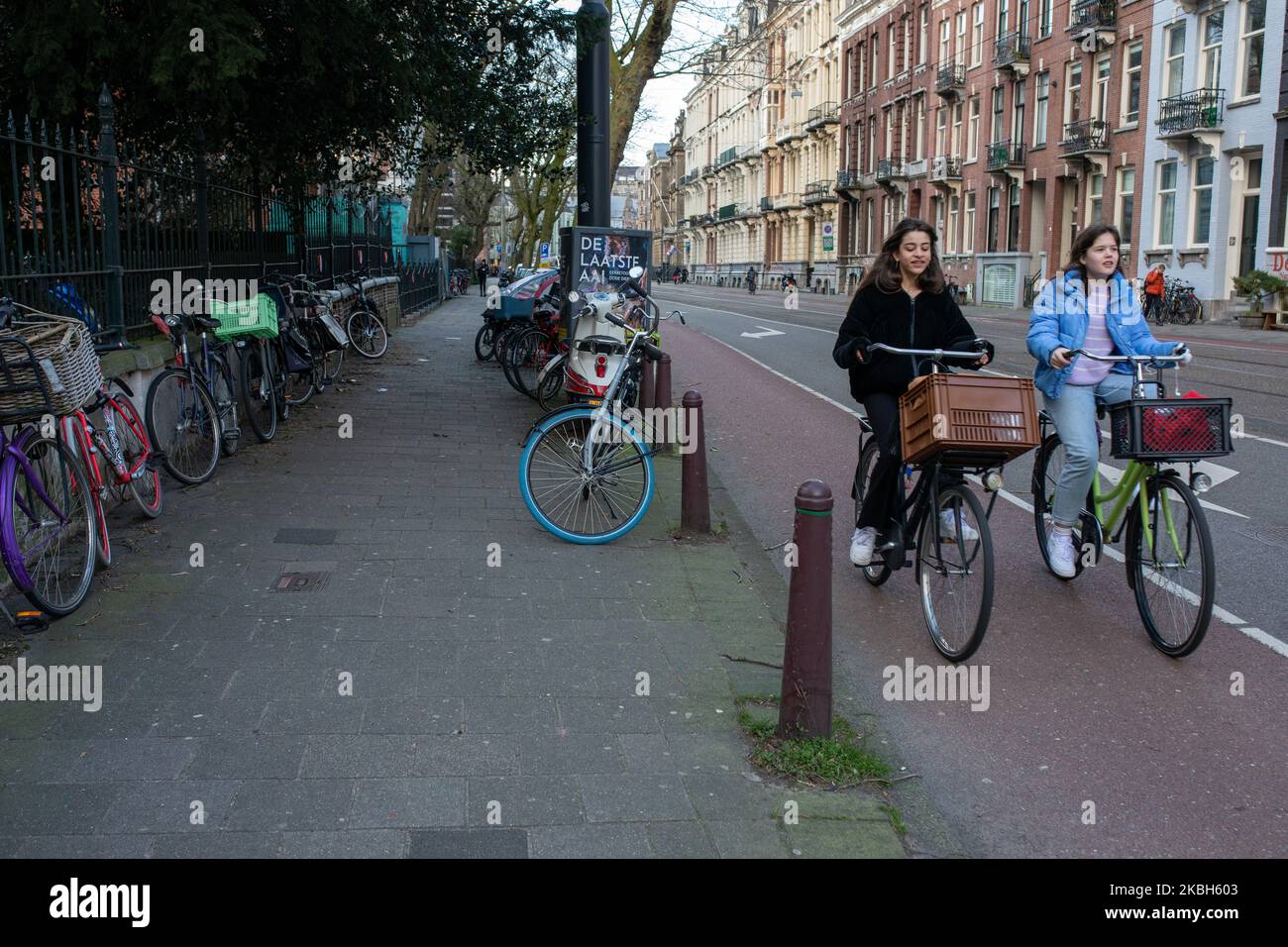 People using bikes in the city and/or electric car charging stations in Amsterdam seen on February 17, 2019. Amsterdam is equipped with an wide network of cycle-paths, so safe and comfortable that even toddlers and elderly people use bikes as the easiest mode of transport. Bikes are commonly used in other cities such as The Hague and Rotterdam. Gasoline and diesel fueled cars and motorcycles will be banned from Amsterdam from 2030 in an effort to clean up the city's air, the Dutch capital's council said in 2019. The use of electric vehicles is increasing in the city. A pass is needed to charge Stock Photo