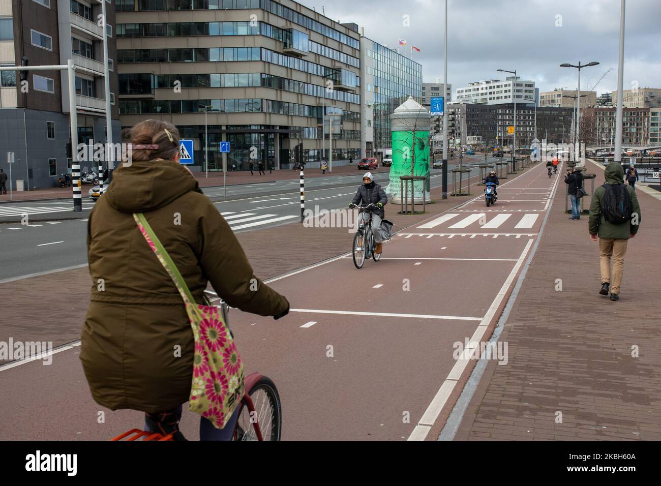 People using bikes in the city and/or electric car charging stations in Amsterdam seen on February 17, 2019. Amsterdam is equipped with an wide network of cycle-paths, so safe and comfortable that even toddlers and elderly people use bikes as the easiest mode of transport. Bikes are commonly used in other cities such as The Hague and Rotterdam. Gasoline and diesel fueled cars and motorcycles will be banned from Amsterdam from 2030 in an effort to clean up the city's air, the Dutch capital's council said in 2019. The use of electric vehicles is increasing in the city. A pass is needed to charge Stock Photo