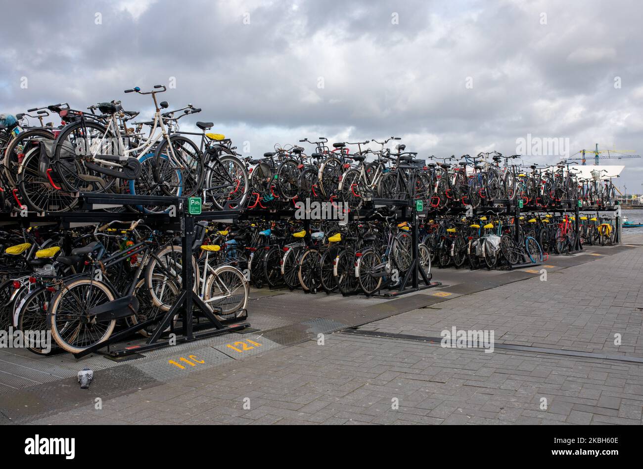 People using bikes in the city and/or electric car charging stations in Amsterdam seen on February 17, 2019. Amsterdam is equipped with an wide network of cycle-paths, so safe and comfortable that even toddlers and elderly people use bikes as the easiest mode of transport. Bikes are commonly used in other cities such as The Hague and Rotterdam. Gasoline and diesel fueled cars and motorcycles will be banned from Amsterdam from 2030 in an effort to clean up the city's air, the Dutch capital's council said in 2019. The use of electric vehicles is increasing in the city. A pass is needed to charge Stock Photo