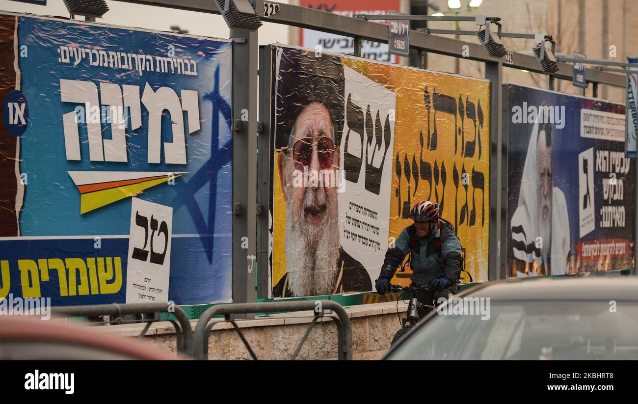 A man cycle by an election campaign poster for Shas, a Haredi religious political party, in central Jerusalem. Israelis head to the polls for the third election in less than a year on March 2nd. On Monday, February 24, 2020, in Jerusalem, Israel. (Photo by Artur Widak/NurPhoto) Stock Photo