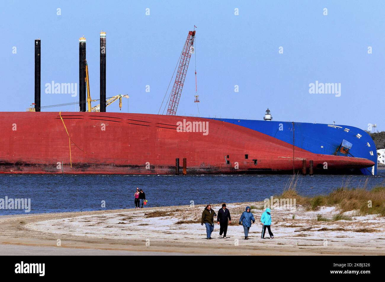 People walk the beach near the Golden Ray cargo ship on February 27