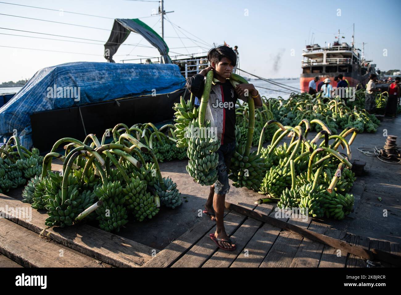 A man carries bananas unloaded from a boat at a jetty in Yangon, Myanmar on March 10, 2020. (Photo by Shwe Paw Mya Tin/NurPhoto) Stock Photo