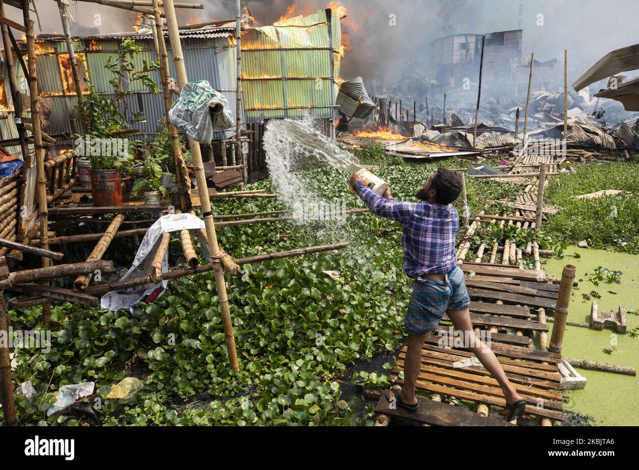 Locals help firefighters douse a fire in a slum in Mirpur, Dhaka, Bangladesh, on March 11, 2020. More than 1,000 shanties of the slum were burnt in the fire. (Photo by Ahmed Salahuddin/NurPhoto) Stock Photo