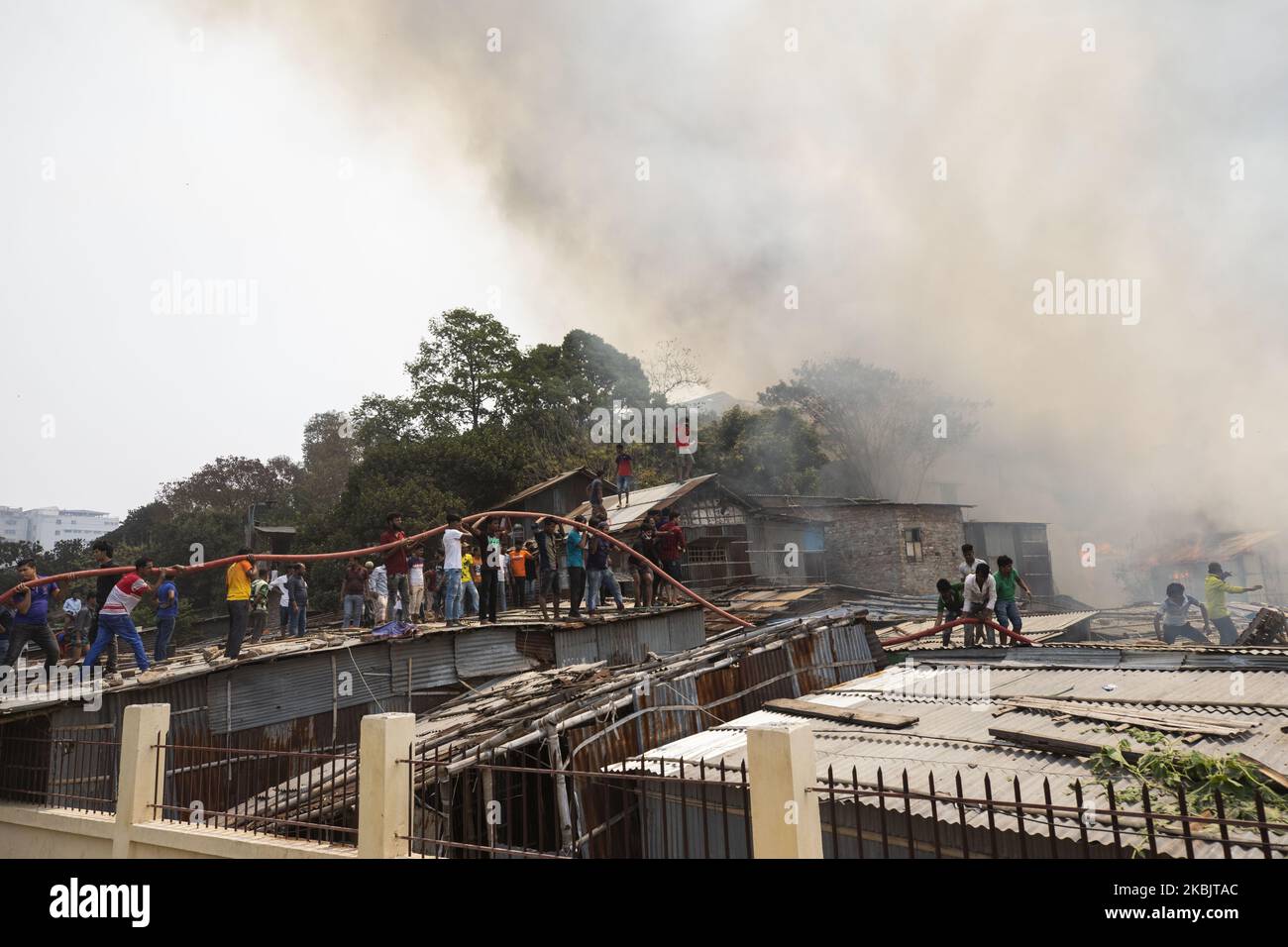 Locals help firefighters douse a fire in a slum in Mirpur, Dhaka ...
