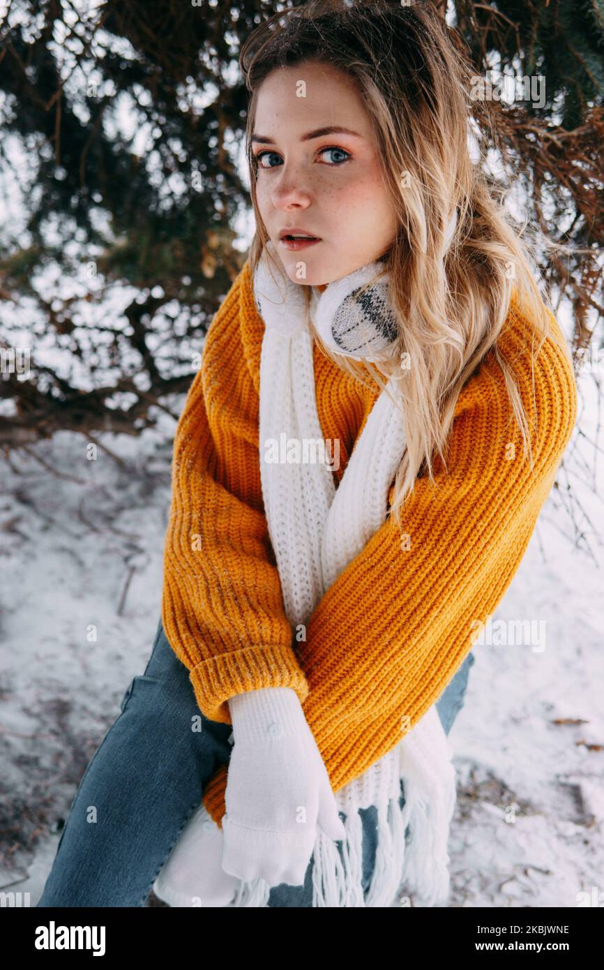 Teen blonde in a yellow sweater outside in winter. A teenage girl on a walk in winter clothes in