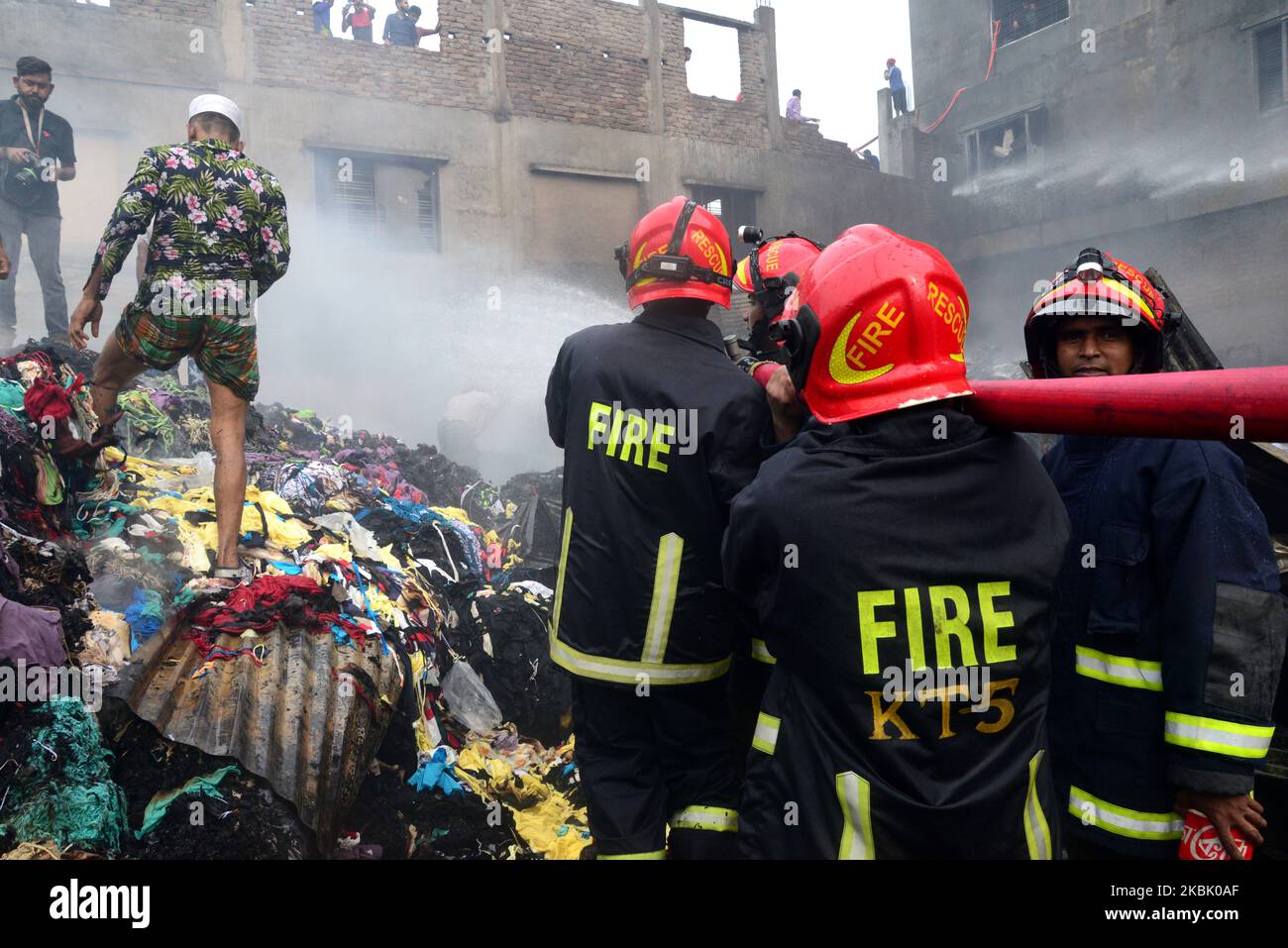 Firefighters and local people work to extinguish a fire at a Jhutpatti ...