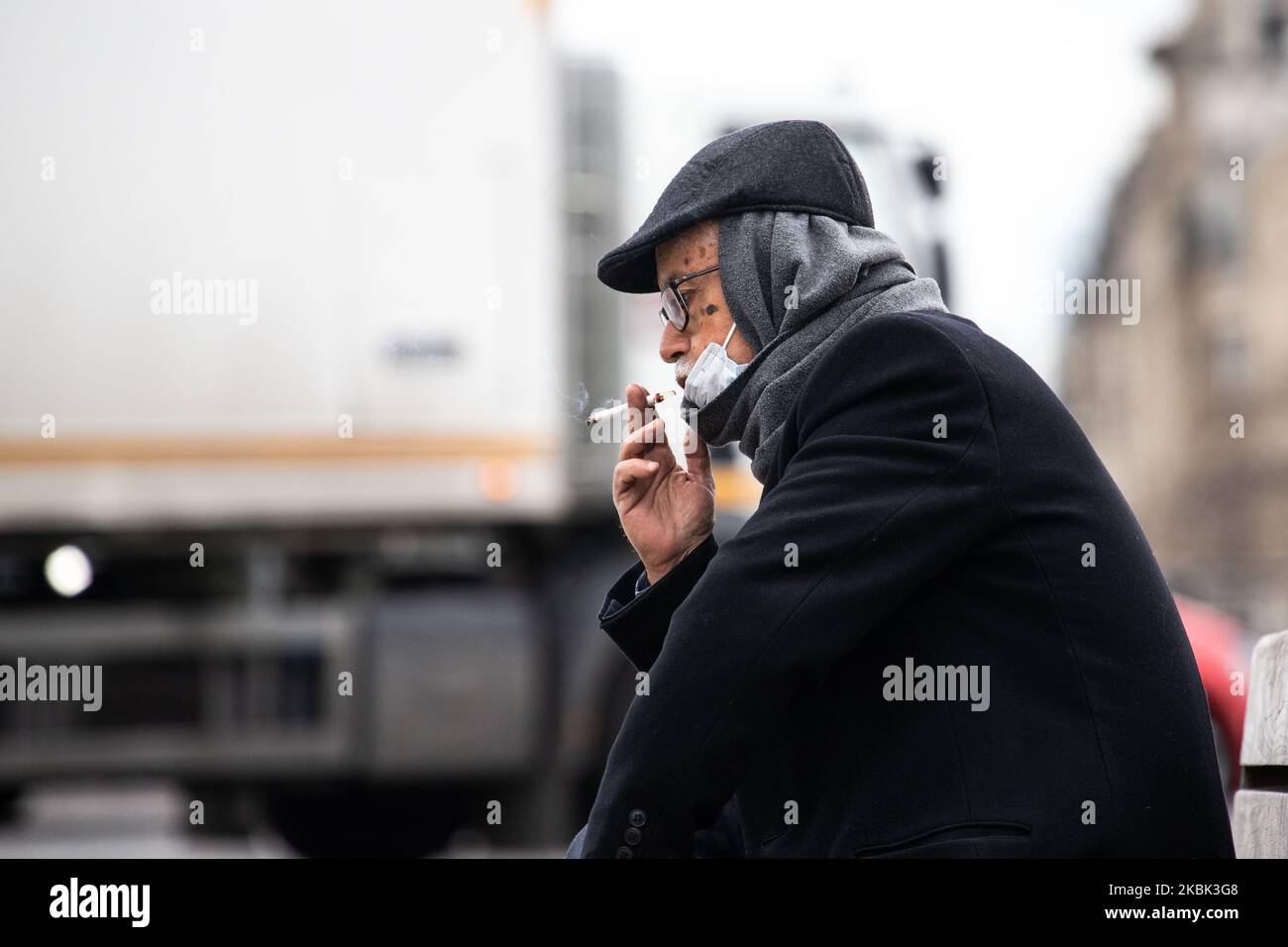 A man wearing a face mask as a preventive measure smokes on March 16, 2020 in Paris, France. France is waiting for the intervention of their president Emmanuel Macron tonight about a possible confinement, lock down, containment, of the french population against the propagation of the Coronavirus,(COVID-19). This morning in Paris the streets were almost empty, the store were closed, as the galeries Lafayette, Cartier, on the Champs Elysees avenue, and the restaurants, as Fouquet's restaurant. (Photo by Jerome Gilles/NurPhoto) Stock Photo