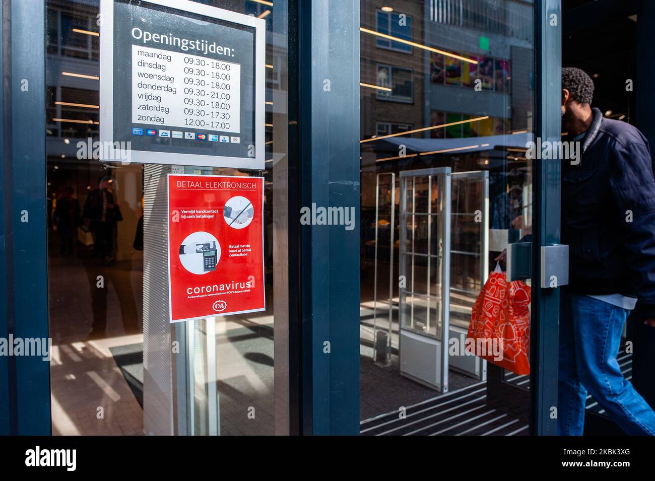 A man is going inside one of the stores with a Coronavirus advice on the door, during the first day of new Coronavirus measures, in Nijmegen. Netherlands. On March 16th, 2020. (Photo by Romy Arroyo Fernandez/NurPhoto) Stock Photo