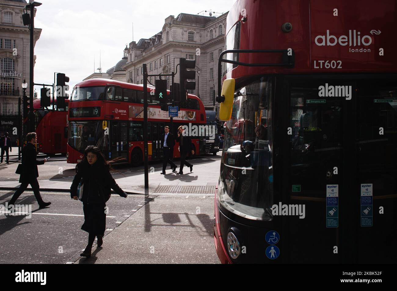 Buses wait at traffic lights in an almost deserted Piccadilly Circus in London, England, on March 17, 2020. It has been suggested that public transport in London could soon be massively scaled back to help stem the tide of covid-19 coronavirus cases. London's streets and squares were noticeably quieter today than just 24 hours ago, albeit not deserted. The emptying-out follows new guidance issued yesterday for people to avoid all non-essential social contact and avoid places such as restaurants and pubs. But the British government has so far not followed the path taken by some other countries  Stock Photo