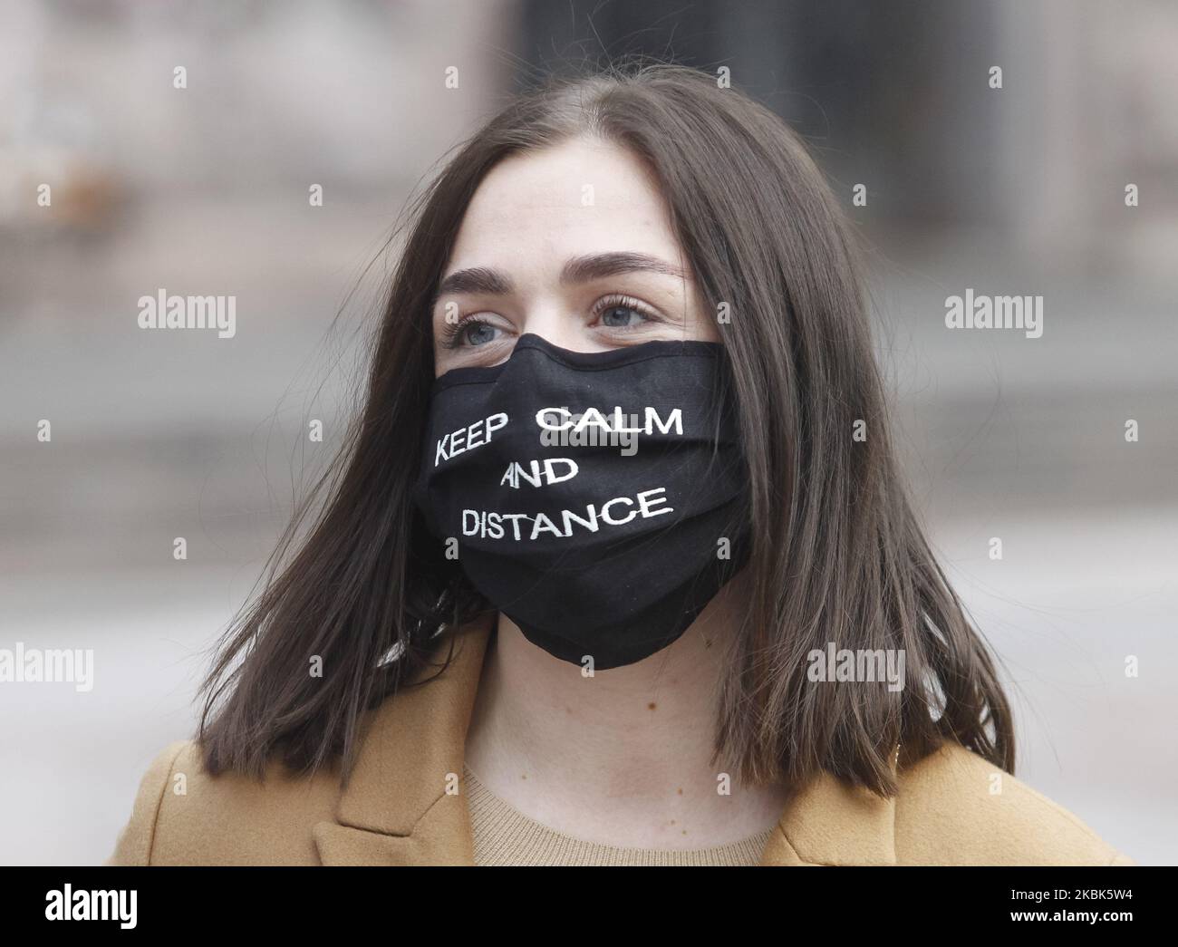 An young woman wearing a protective face mask as a preventive measure against the COVID-19 coronavirus walks in Kyiv, Ukraine, on 17 March, 2020. To stem the spread of the coronavirus COVID-19 from March 18, Ukraine suspends railway, air, bus intercity and interregional passenger traffic inside the country, and from March 17 the subway stops working in cities, bars, restaurants, cafes, shopping and entertainment centers temporarily suspend their work in Ukraine. (Photo by STR/NurPhoto) Stock Photo