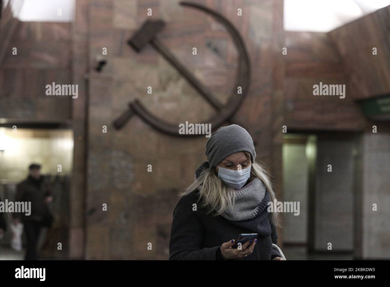 A woman in a protective mask walks near the symbol of the Soviet Union (hammer and sickle) at the Proletarskaya station. due to the coronavirus outbreak, the number of metro users has decreased by 25 percent. Saint Petersburg, Russia. March 23, 2020 (Photo by Valya Egorshin/NurPhoto) Stock Photo