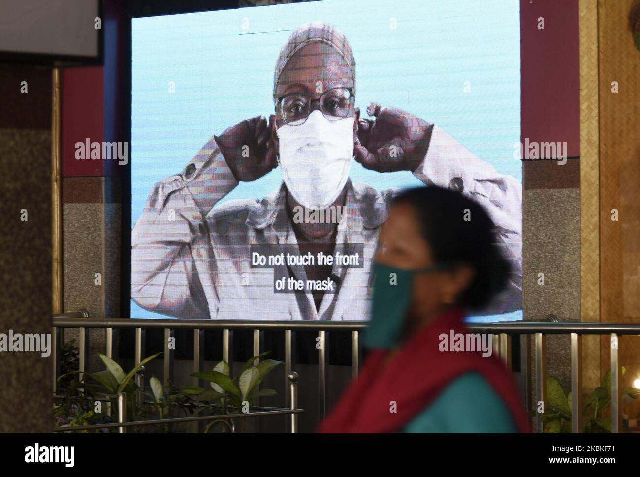 In a large display, a video showing how to use mask, as a railway worker walking wearing protective mask avid corona virus scare, at Guwahati Railway Station, in Guwahati, Assam, India on 24 March 2020. (Photo by David Talukdar/NurPhoto) Stock Photo