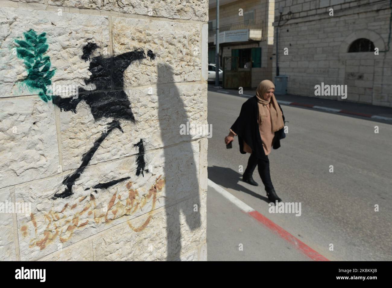 A lady walks by a politicalgraffiti near the wall separting Israel and the West Bank in Bethlehem. On Thursday, March 5, 2020, in Bethlehem, Palestine (Photo by Artur Widak/NurPhoto) Stock Photo
