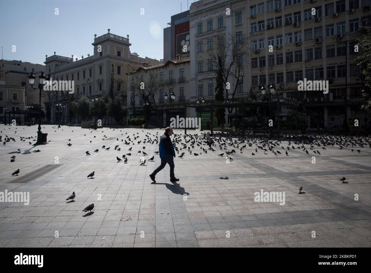 A man is passing by an empty square during the nationwide lockdown to contain the spread of the Coronavirus disease, in central Athens, Greece on March 30, 2020. (Photo by Nikolas Kokovlis/NurPhoto) Stock Photo