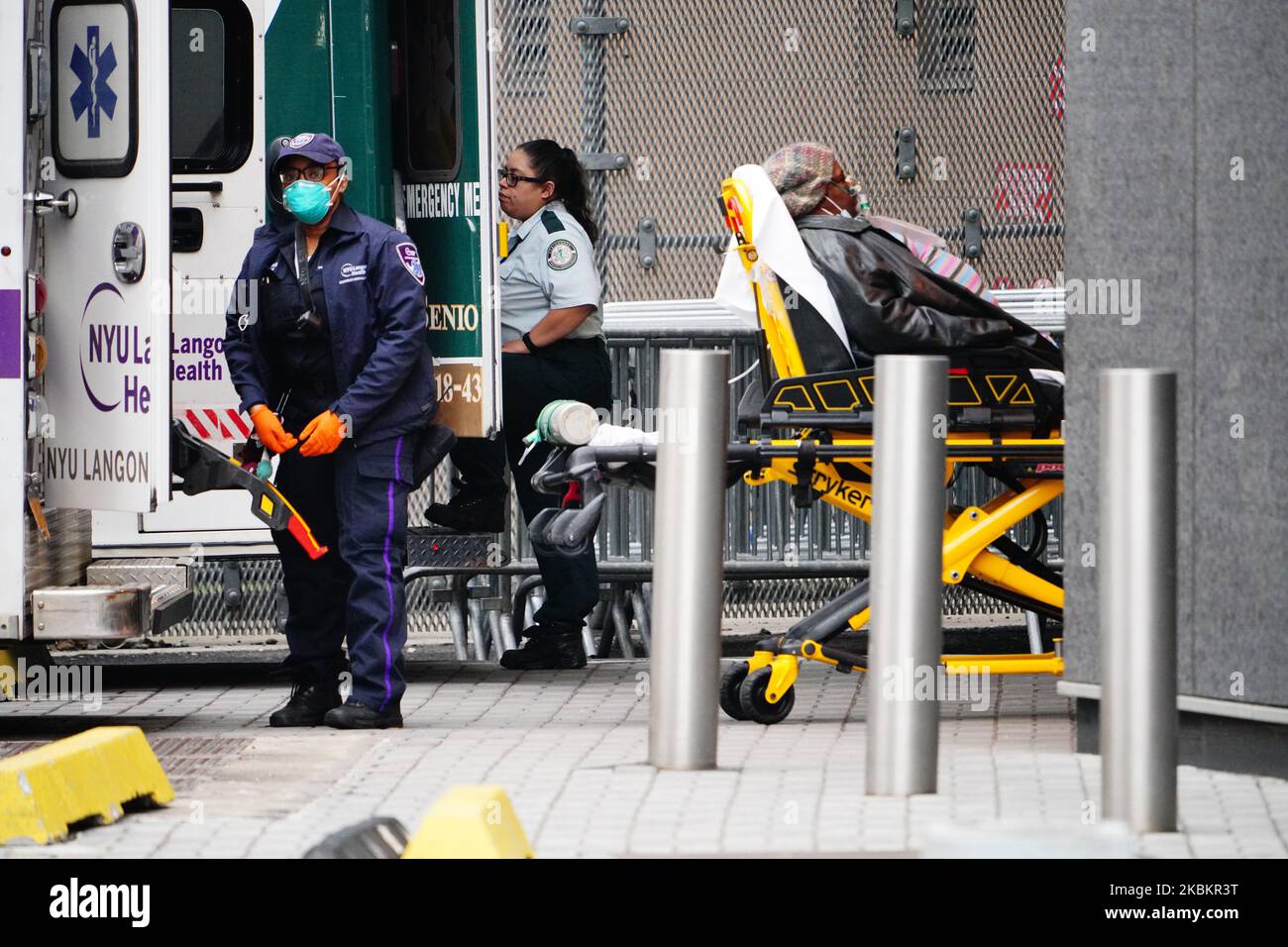 An elderly patient wearing a mask is seen being wheeled out of an ambulance at Bellevue Hospital
