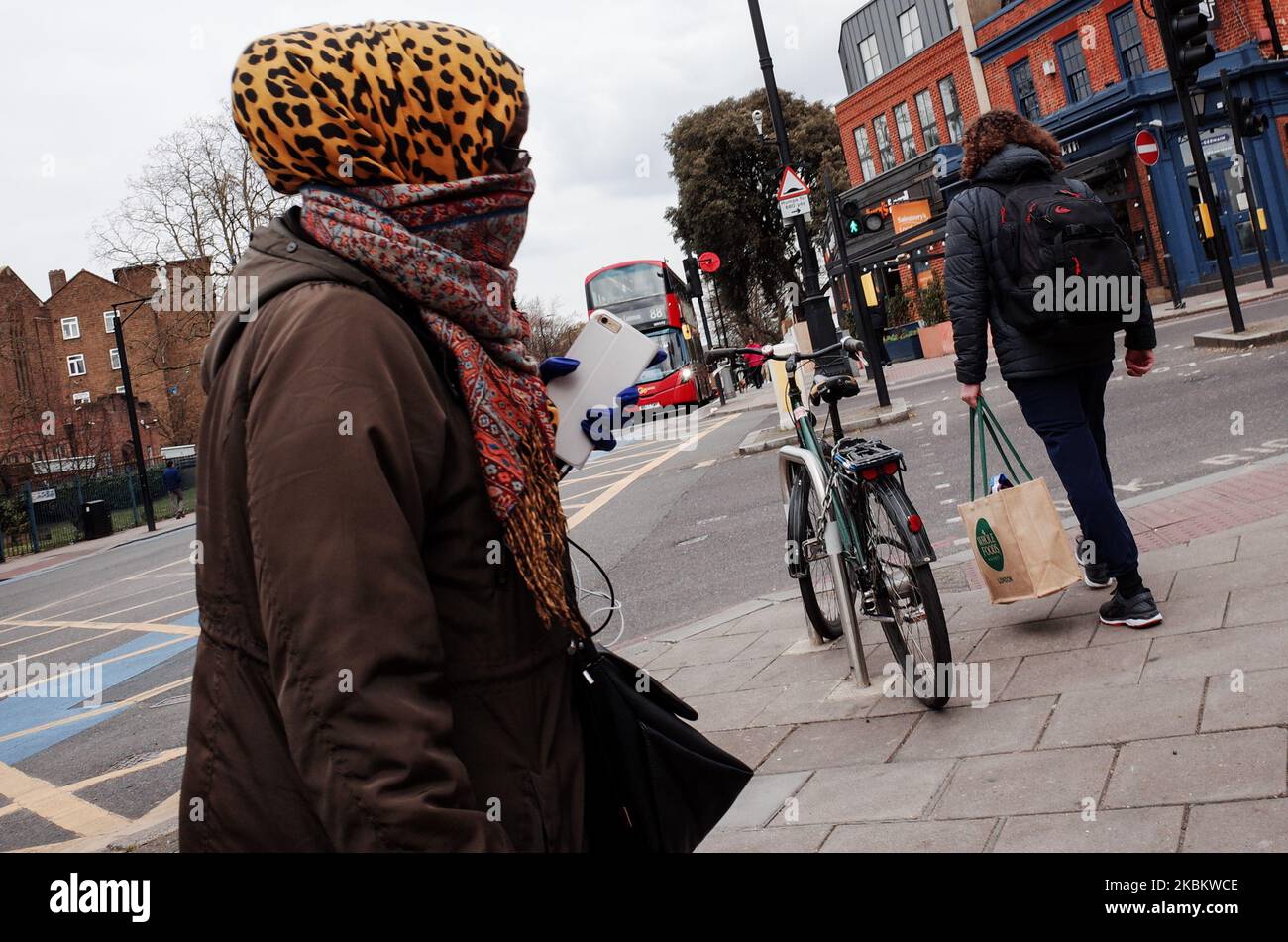 A woman covering her face with a scarf walks outside Clapham North station in the borough of Lambeth in London, England, on April 1, 2020. Official figures report that Lambeth currently has 418 recorded cases of the covid-19 coronavirus, higher than any other local authority district in London and fourth among local authorities in England as a whole (behind Sheffield, Hampshire and Birmingham). The borough was previously trailing the neighbouring south London district of Southwark, which remains similarly hard-hit, currently with 415 cases. (Photo by David Cliff/NurPhoto) Stock Photo