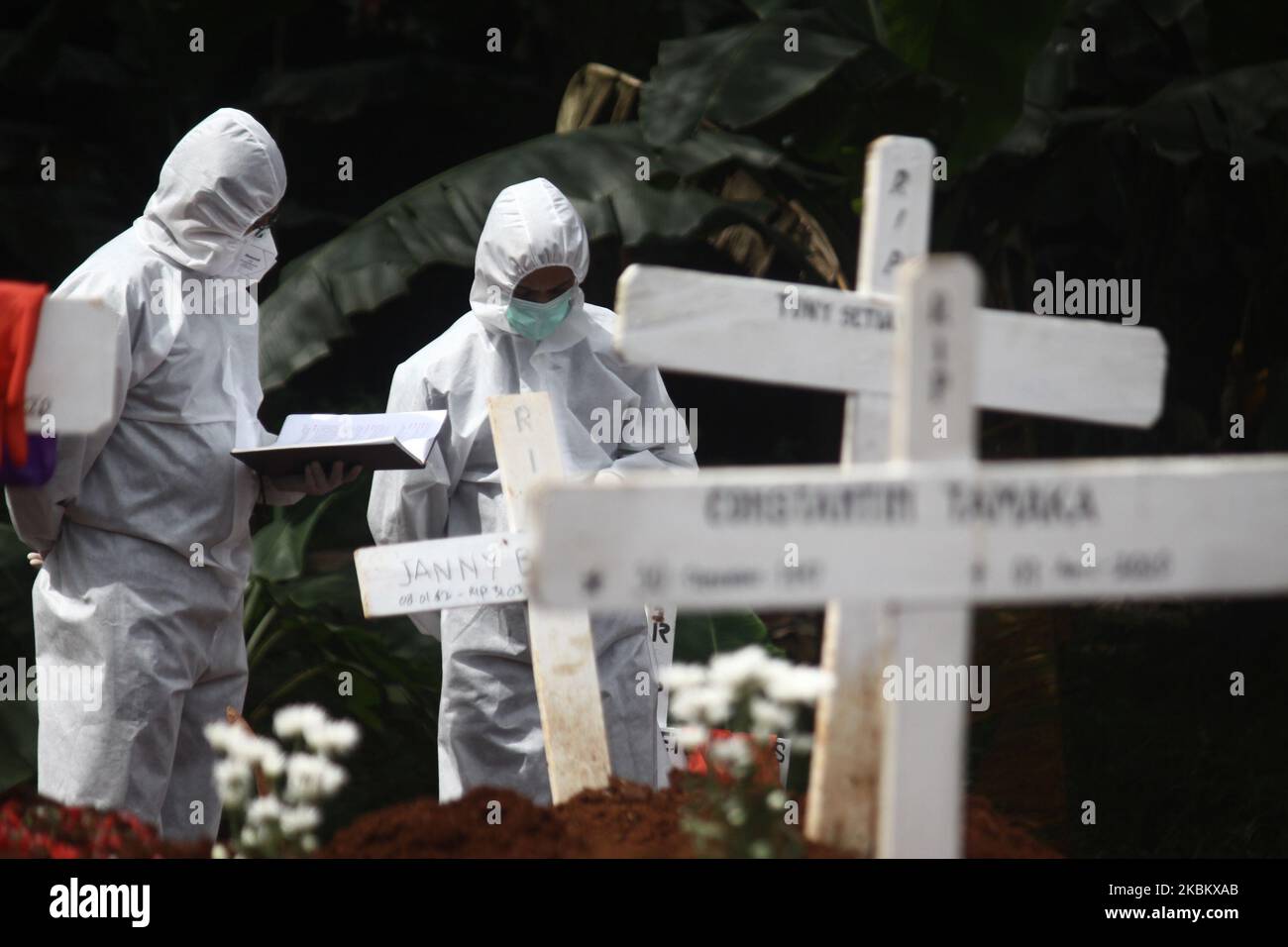 Families pray at the grave of the coronavirus (Covid-19) victims at the