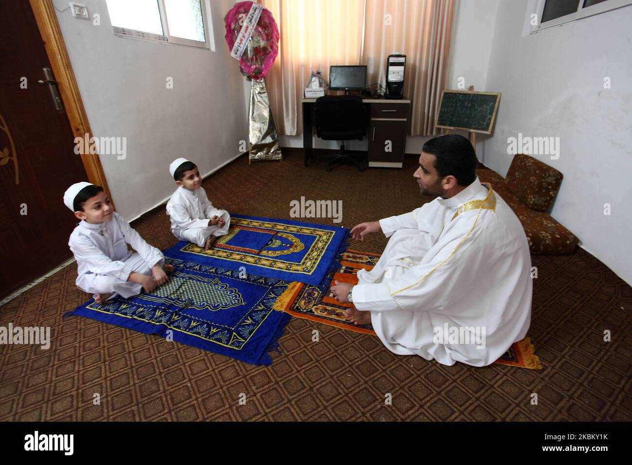Palestinian preacher Mustafa al-Qishawi, 34, who usually calls for prayers and leads them at a mosque, leads the Friday prayer for his with his children at home in Gaza City, on April 3, 2020, amid the closure of mosques due to the novel coronavirus pandemic. (Photo by Majdi Fathi/NurPhoto) Stock Photo