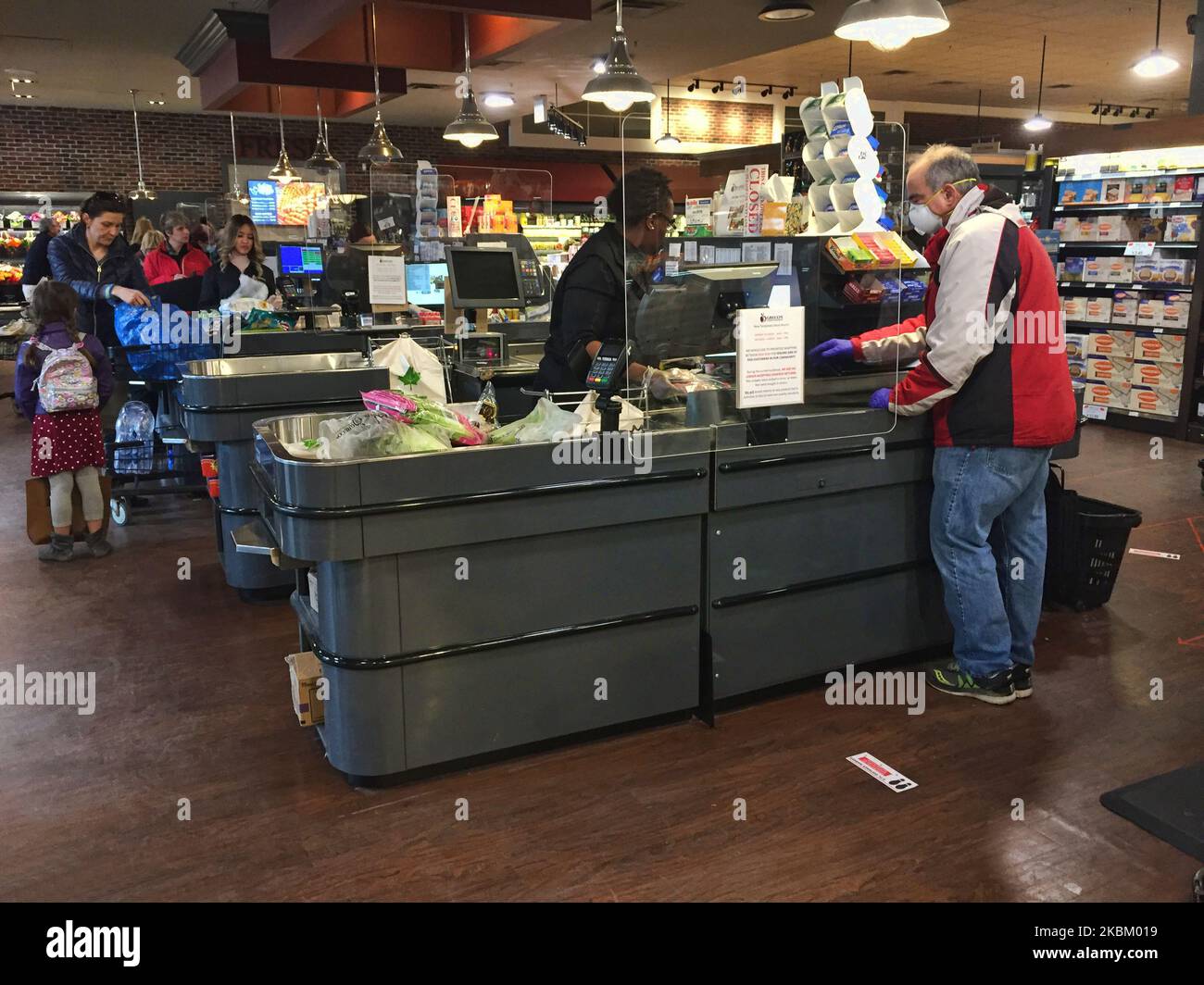 Cashiers behind newly installed plexiglass (acrylic) shields to protect them from the novel coronavirus (COVID-19) at a grocery store on April 03, 2020 in Toronto, Ontario, Canada. Grocery stores and other retailers have began installing plexiglass shields at checkouts and enforcing social distancing (physical distancing) to slow the spread of COVID-19. (Photo by Creative Touch Imaging Ltd./NurPhoto) Stock Photo