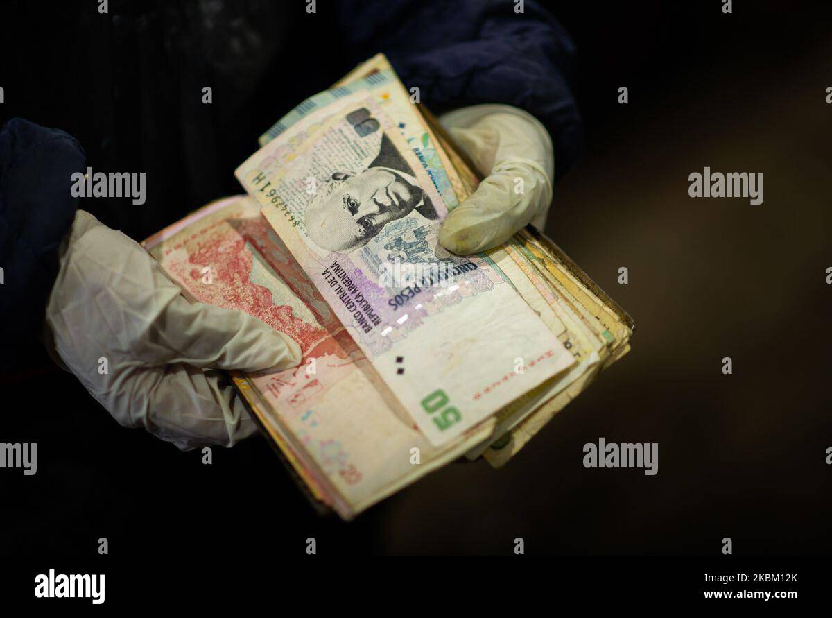 A seller show the Argentina's currency as she waits for customers at the Central Market in Buenos Aires, Argentina, saturday, April 3, 2020. (Photo by Mario De Fina/NurPhoto) Stock Photo