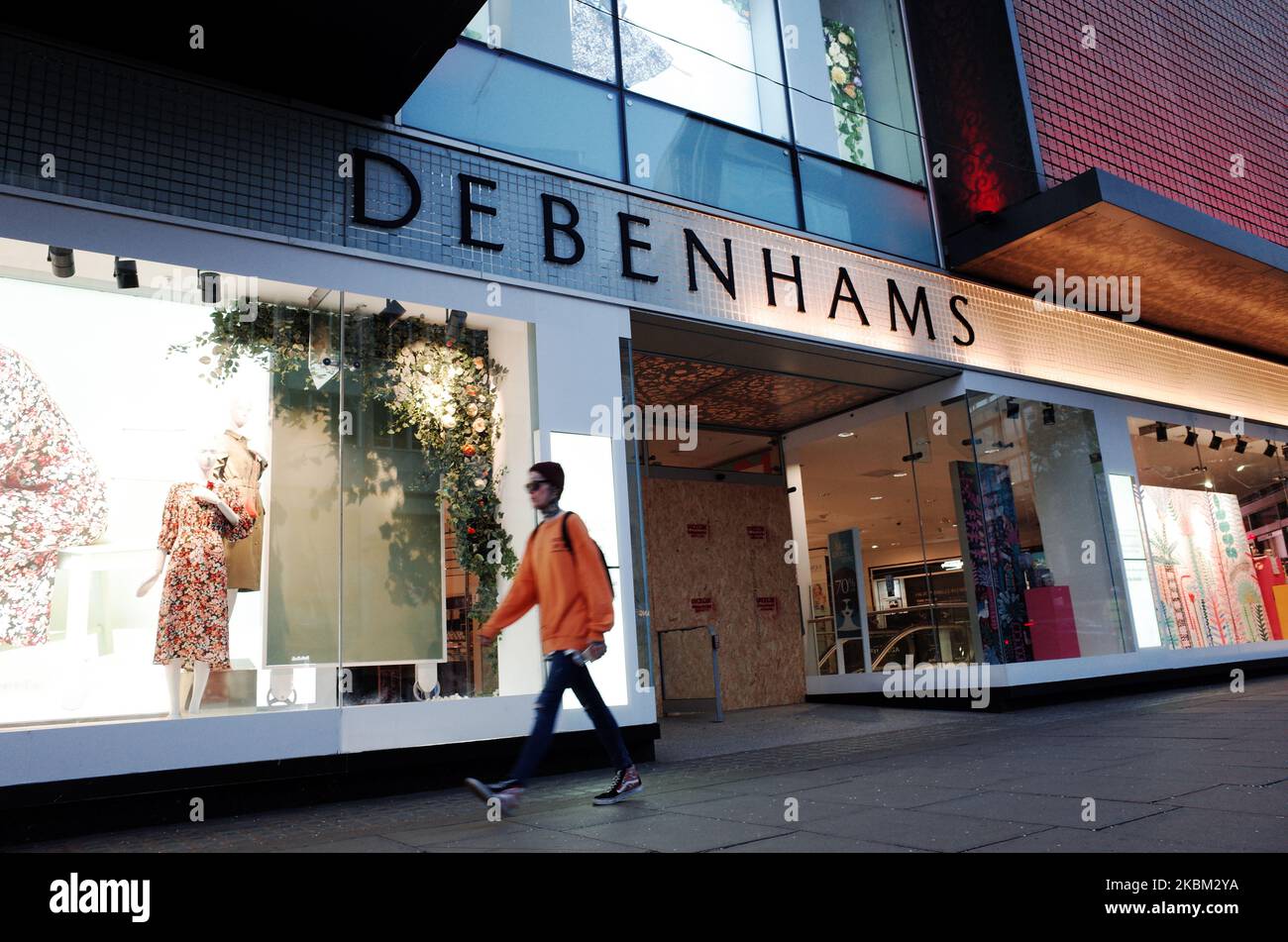 A woman walks past the boarded-up flagship branch of department store chain Debenhams on a near-deserted Oxford Street in London, England, on April 6, 2020. Debenhams announced today that it was having to file for administration as a consequence of having to shut all its stores across the UK under the covid-19 coronavirus lockdown. This is to be the second time in a year that the struggling retailer has filed for administration. Its present predicament comes not long after its permanent closure of 22 stores, resulting in more than 700 job losses, with a further 28 already slated for closure in Stock Photo