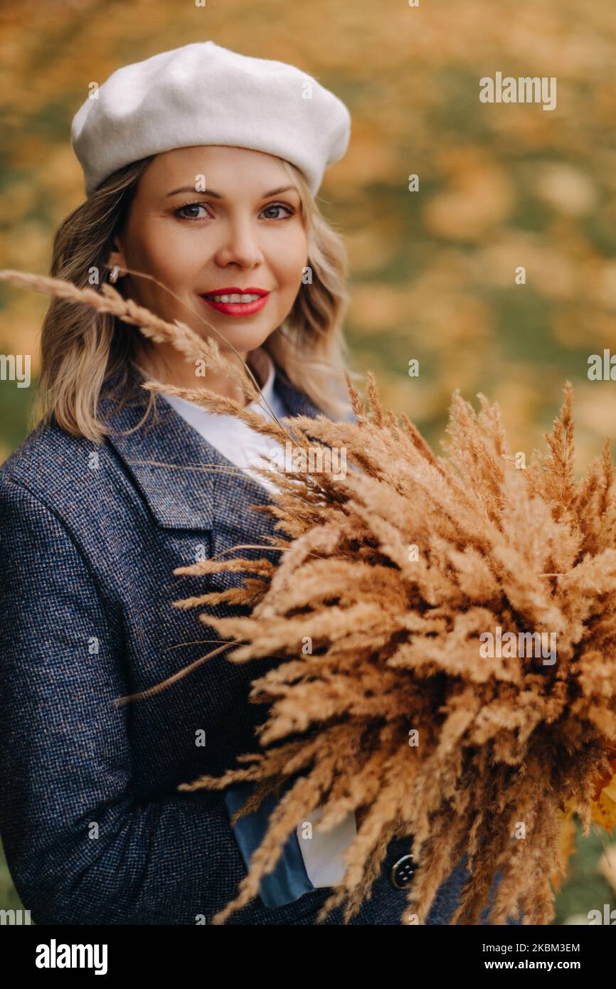 Portrait of a Girl in a jacket and birette with an autumn bouquet in an autumn park Stock Photo