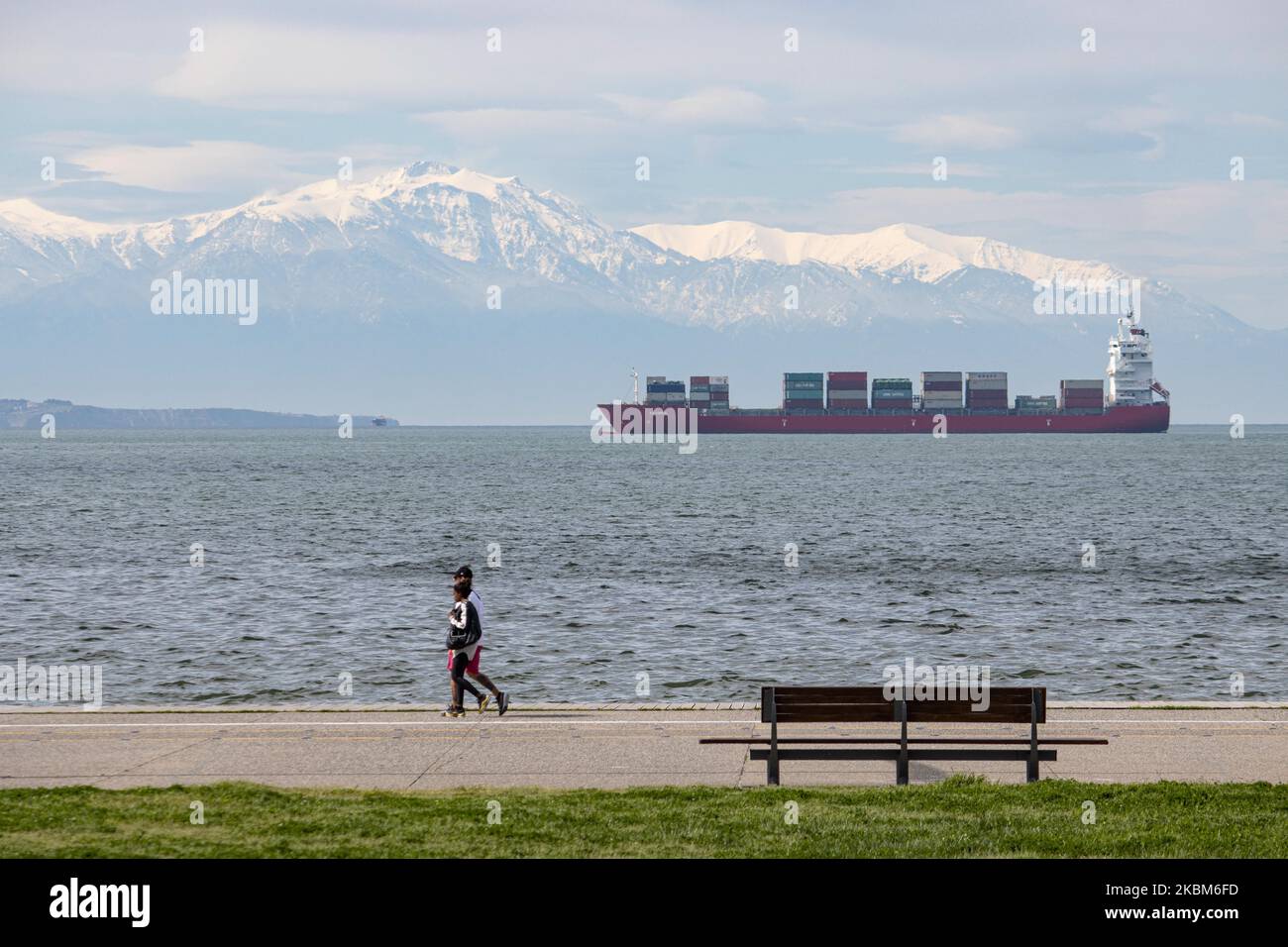 A freight vessel as seen from the seafront of Thessaloniki city anchored at Thermaikos Gulf, Aegean Sea in Greece on April 7, 2020. The cargo ship carries containers shipment and is under the name Ef Emira, with IMO registration number 9357810, sailing under the flag of Marshall Islands. The ship waits to unload its merchandise at the Port of Thessaloniki, the second-largest container port in Greece but there is a delay in the port due to Covid-19 Coronavirus Pandemic. Snow covered Mount Olympus is visible in the background. (Photo by Nicolas Economou/NurPhoto) Stock Photo