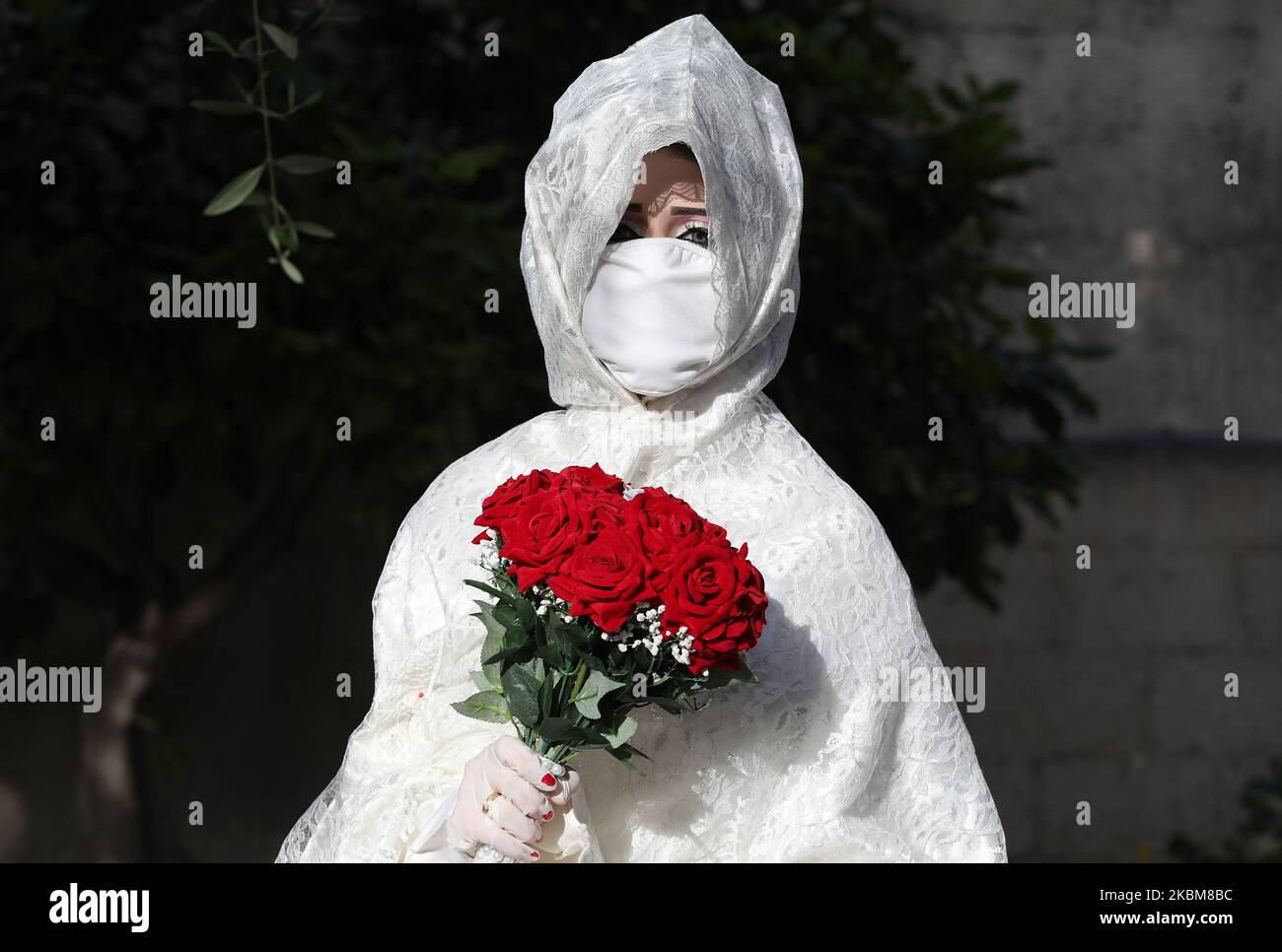 Palestinian bride Nermin wearing a protective mask amid the COVID-19 epidemic, poses for pictures during a photoshoot before their wedding ceremony in Gaza City, on April 10, 2020. (Photo by Majdi Fathi/NurPhoto) Stock Photo