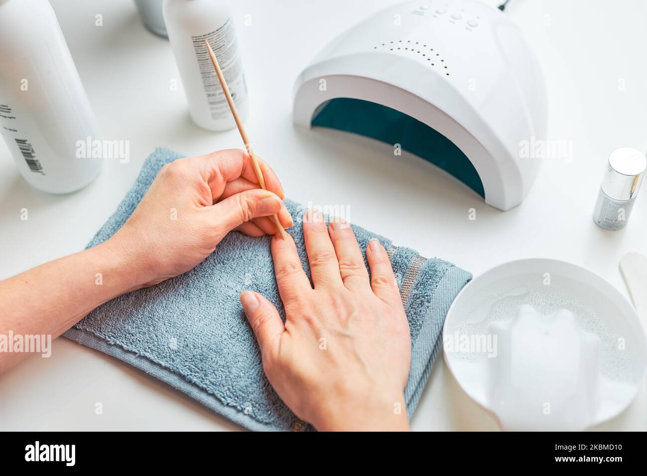 Woman preparing nails to apply gel hybrid polish using UV lamp. Beauty