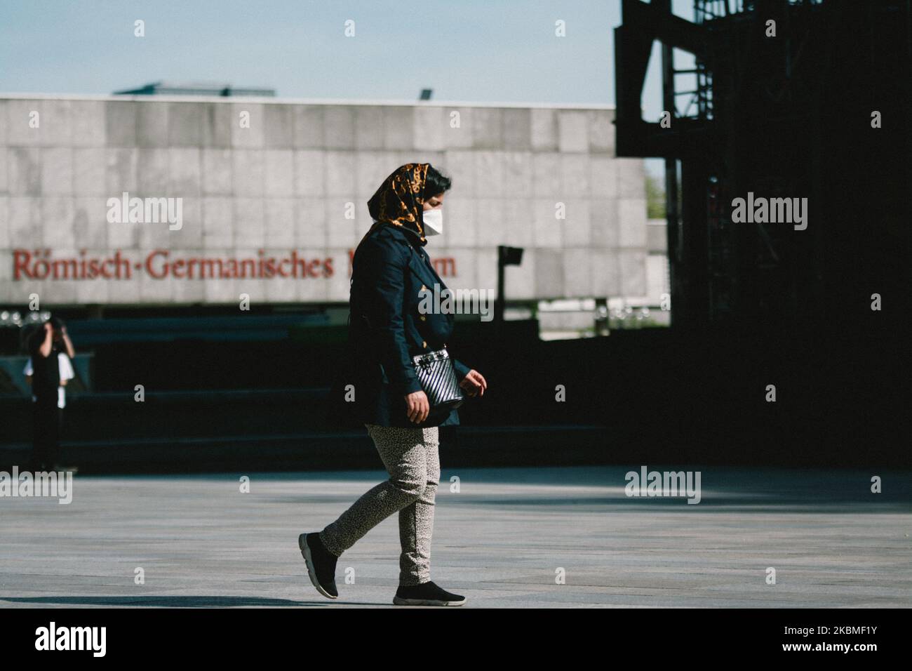 a woman, wearing mouth mask, walk in front of Roemisch Germanisches Museum in Cologne, Germany, on April 15, 2020. (Photo by Ying Tang/NurPhoto) Stock Photo