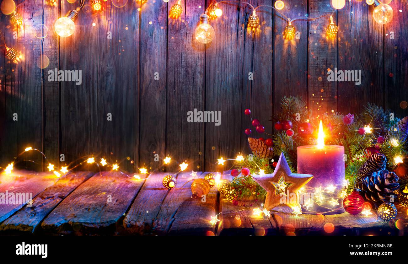 Advent - Candle Glowing In Christmas Lights On Wooden Table With Decoration - Defocused Bokeh And Glittering Effect On Background Stock Photo
