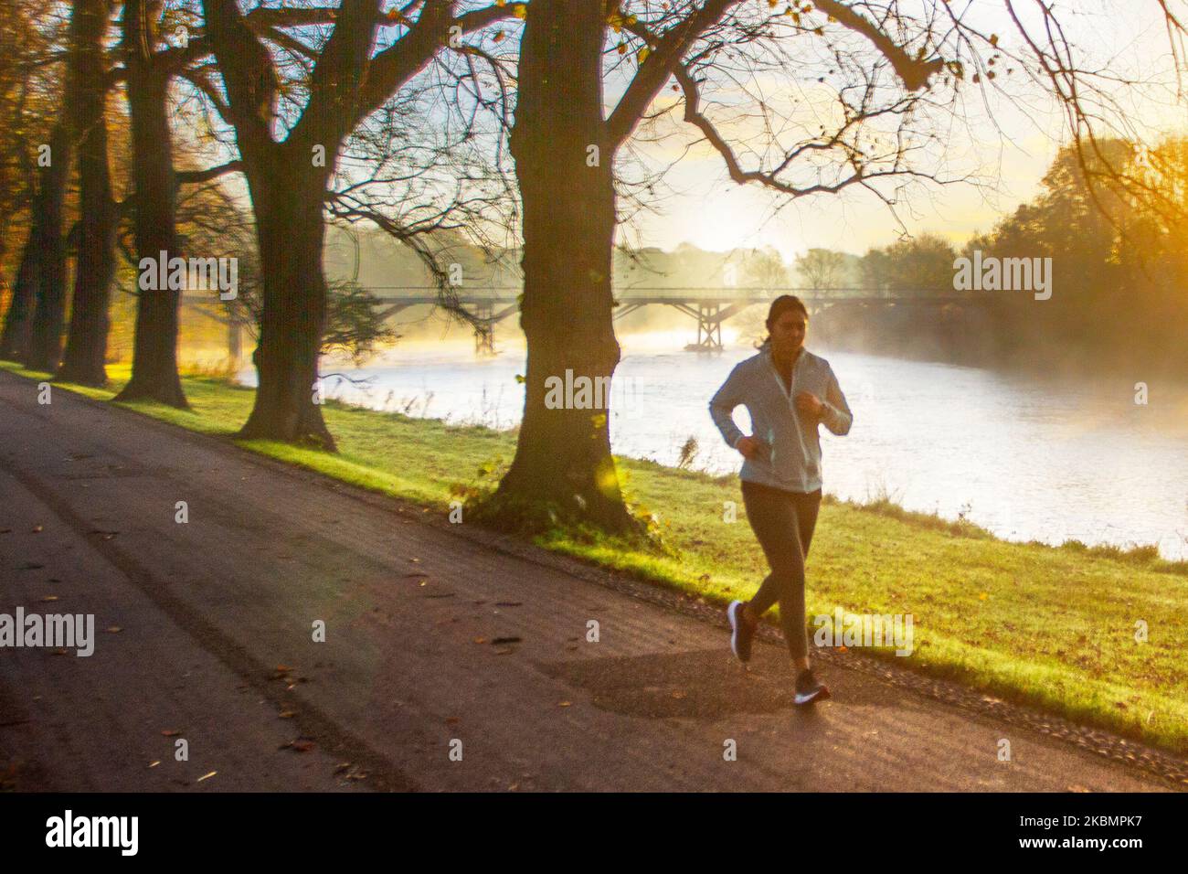 Preston, Lancashire. UK Weather 4 November, 2022.  Cold frosty, misty morning as the sun rises over the River Ribble and local residents take light exercise along the riverside walk in Avenham Park. Sunny spells are forecast after the first frost of Autumn.  Credit; MediaWorldImages/AlamyLiveNews Stock Photo