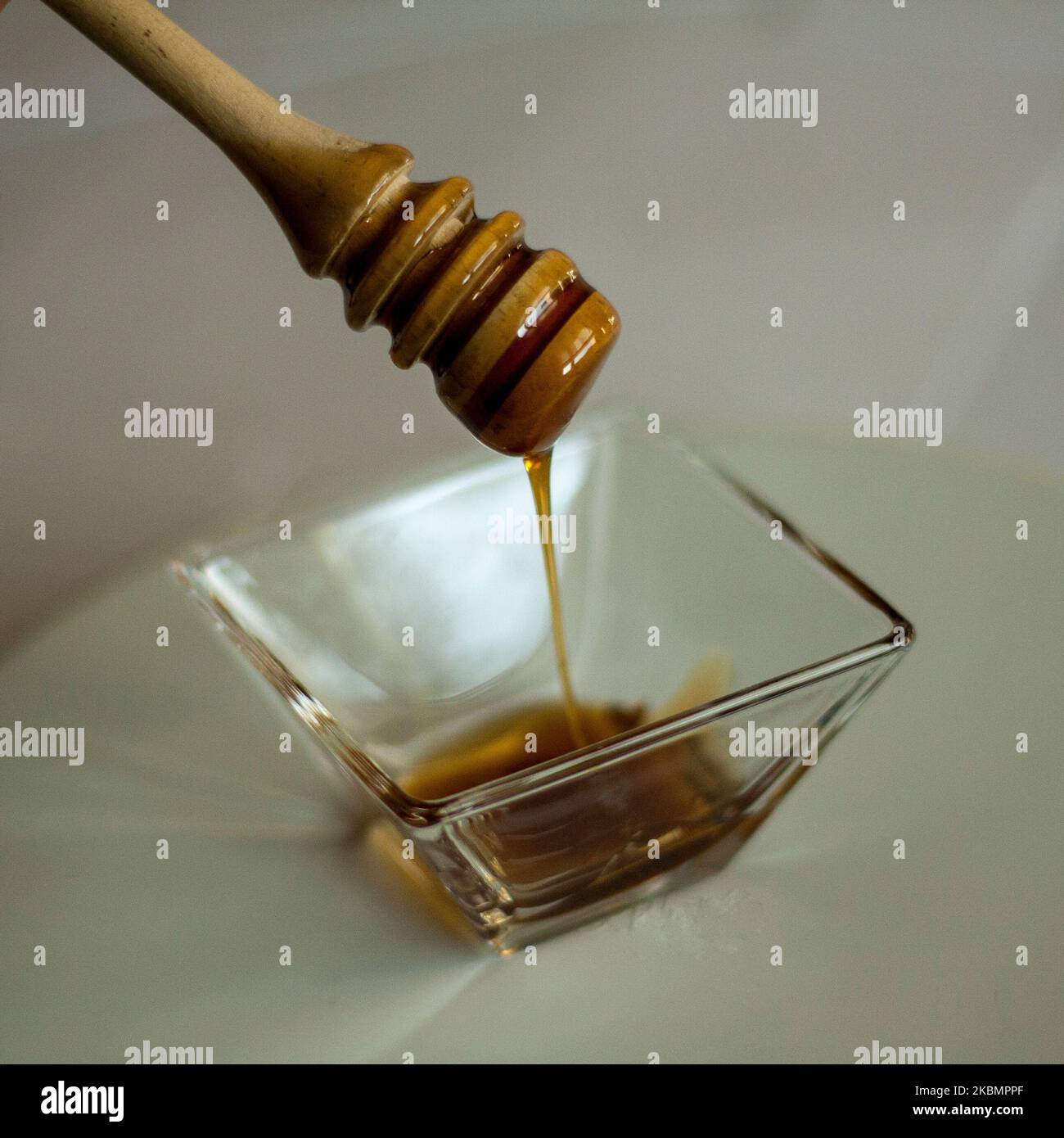 tablespoons of freshly picked honey dripping into a bowl Stock Photo