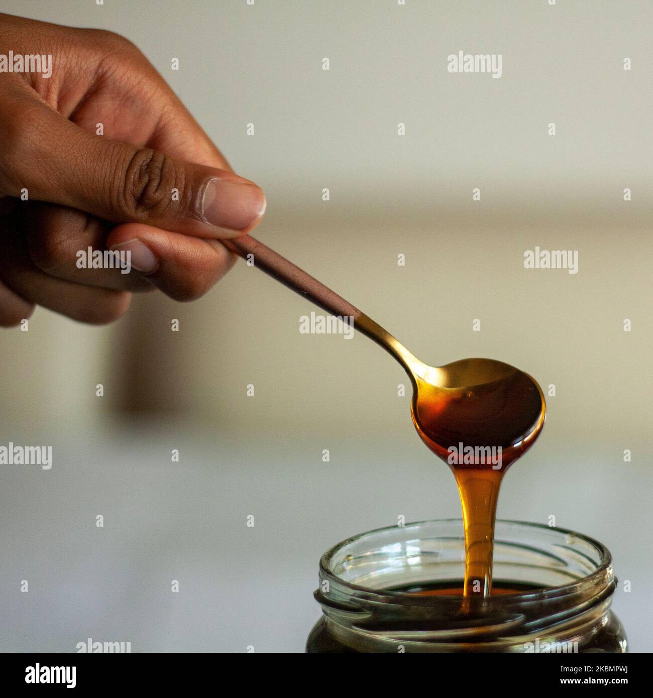 tablespoons of freshly picked honey dripping into a bowl Stock Photo