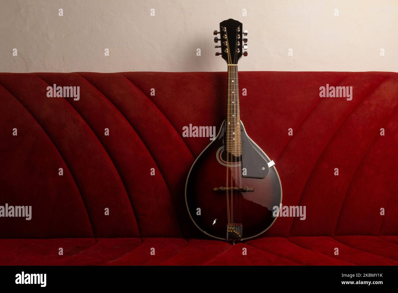 https://c8.alamy.com/comp/2KBMY1K/mandolin-resting-on-an-old-red-sofa-2KBMY1K.jpg