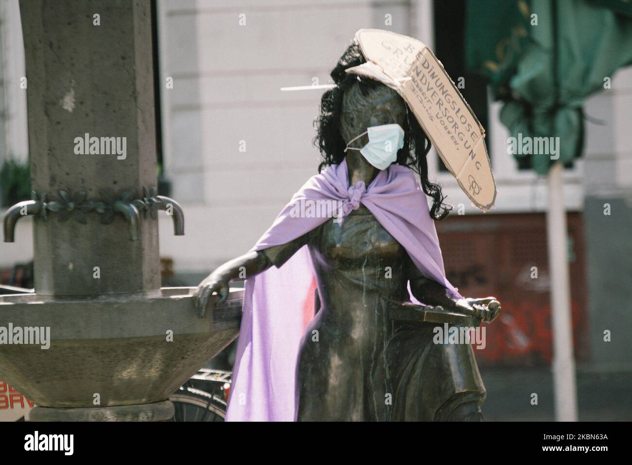 The sculpture with face mask and placard which is written 'Action for national crisis help for housing and health care', is seen in Cologne, Germany, on May 1, 2020. (Photo by Ying Tang/NurPhoto) Stock Photo
