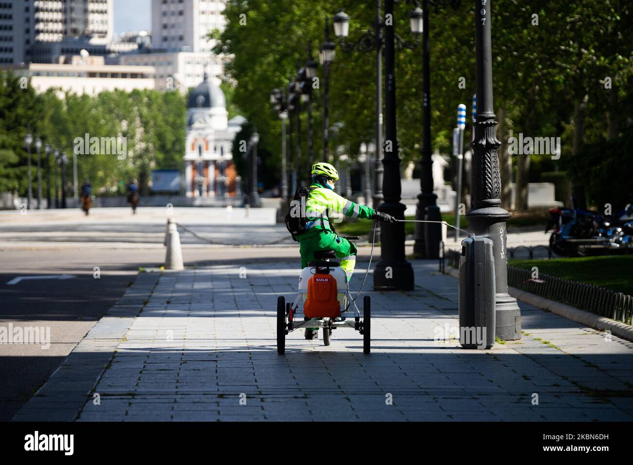 Madrid municipal worker disinfecting a wastebasket located in front of