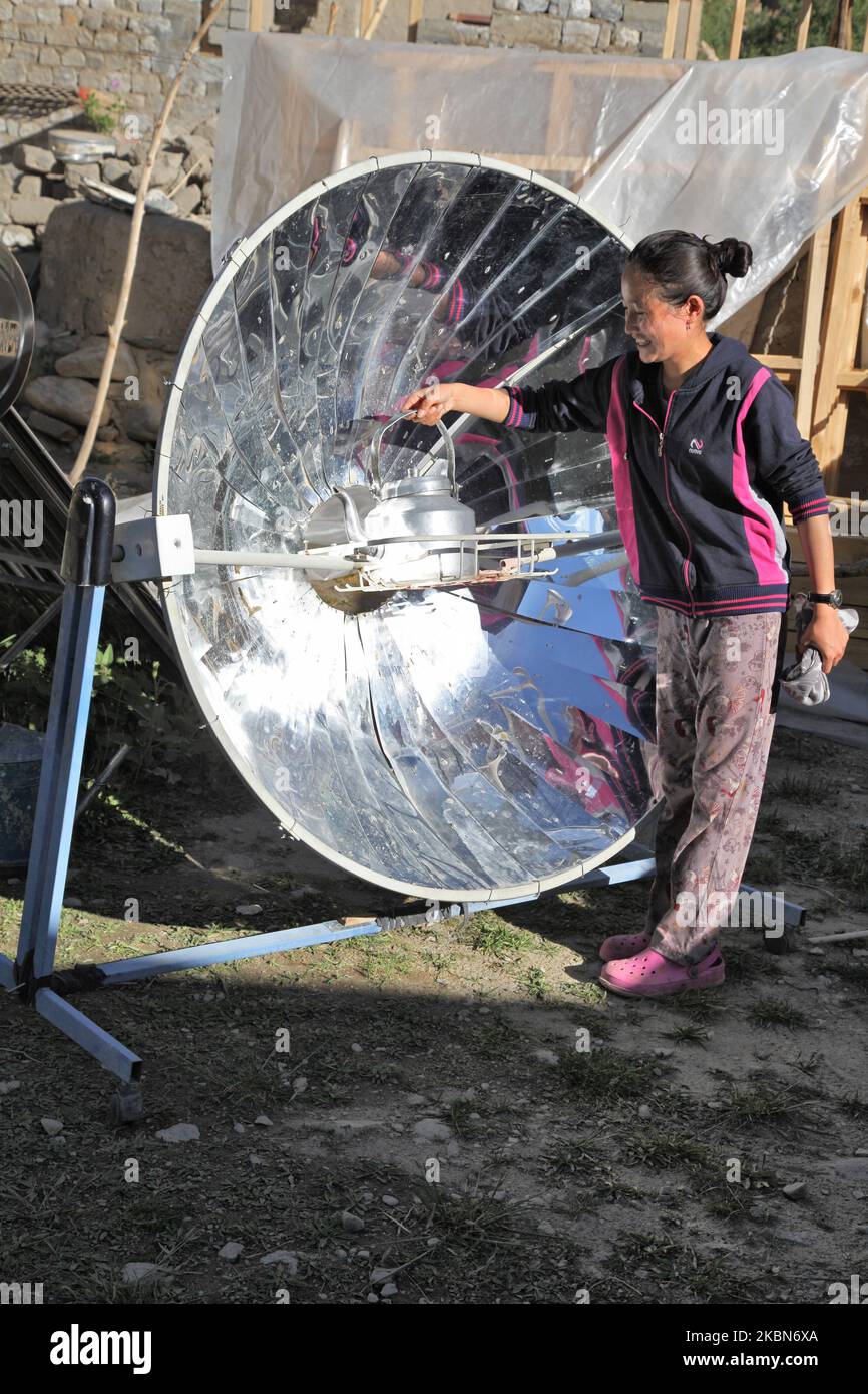 Ladakhi girl uses a parabolic solar cooker to heat water for tea outside her home in the small village of Tangtse, Ladakh, Jammu and Kashmir, India. (This image has a signed model release available) (Photo by Creative Touch Imaging Ltd./NurPhoto) Stock Photo
