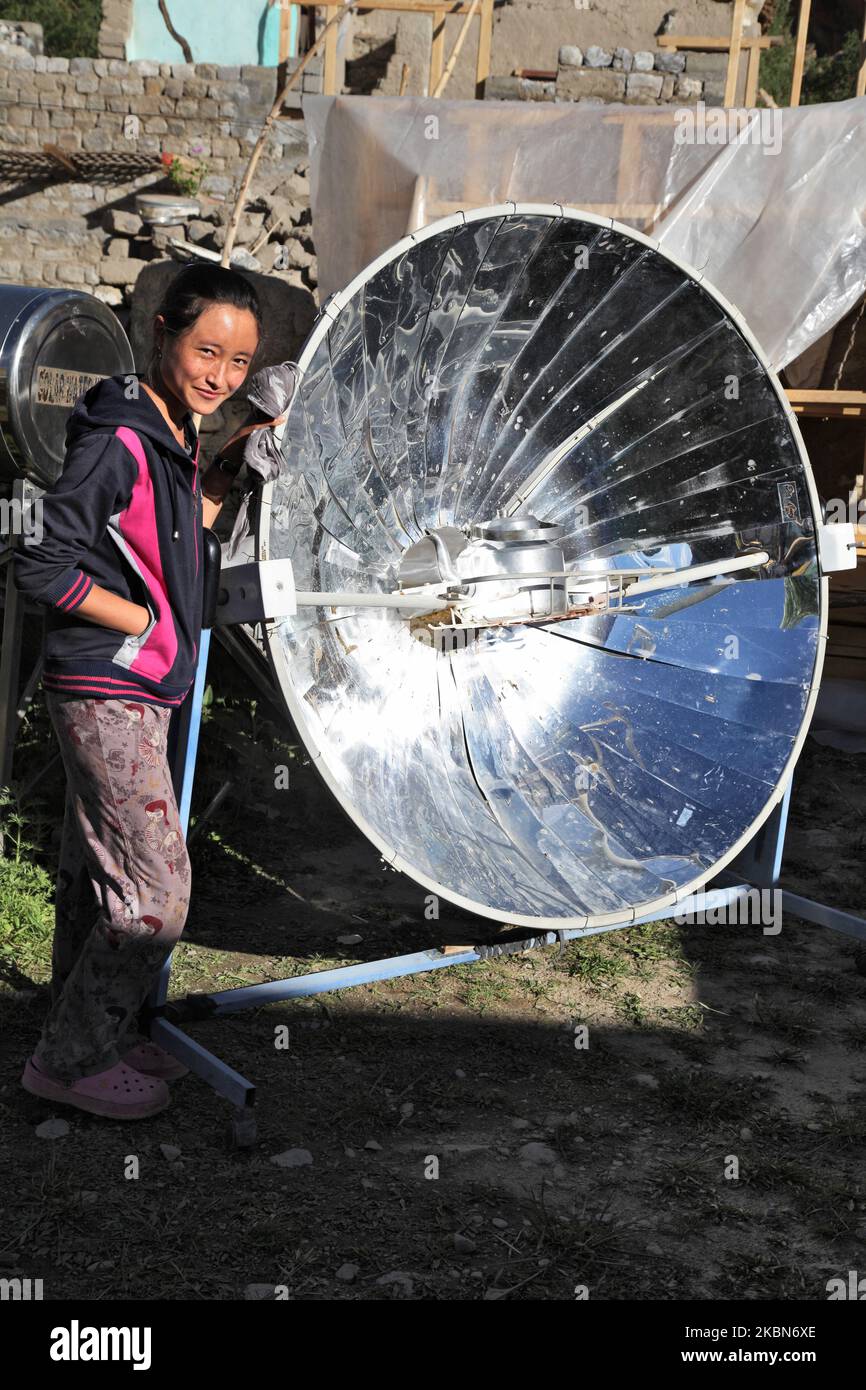 Ladakhi girl uses a parabolic solar cooker to heat water for tea outside her home in the small village of Tangtse, Ladakh, Jammu and Kashmir, India. (This image has a signed model release available) (Photo by Creative Touch Imaging Ltd./NurPhoto) Stock Photo