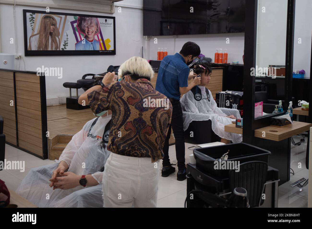 Hairdressers wear face shields cut a customer's hair as following