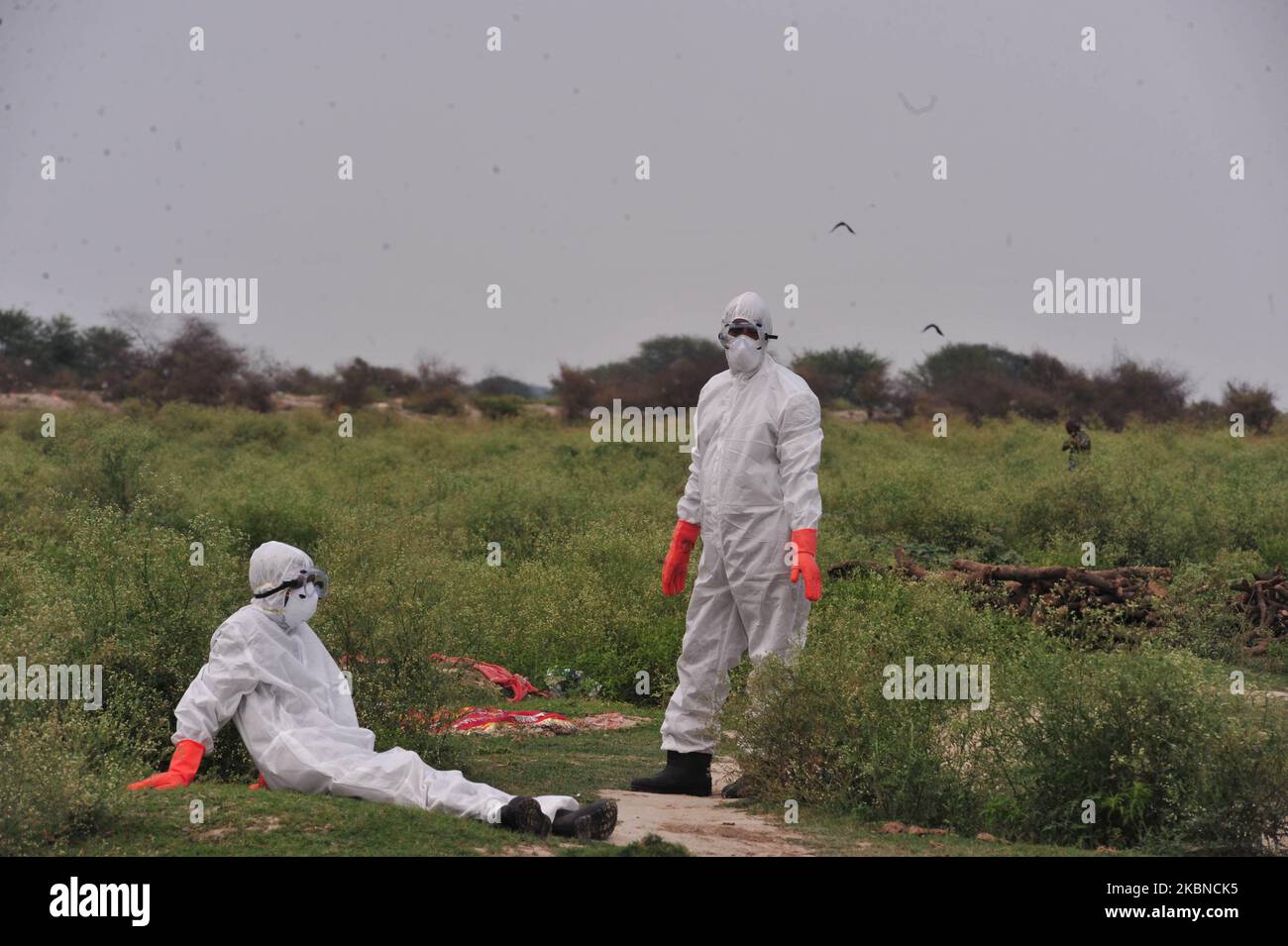 Health workers in protective gear ,take rest after carrying the dead ...