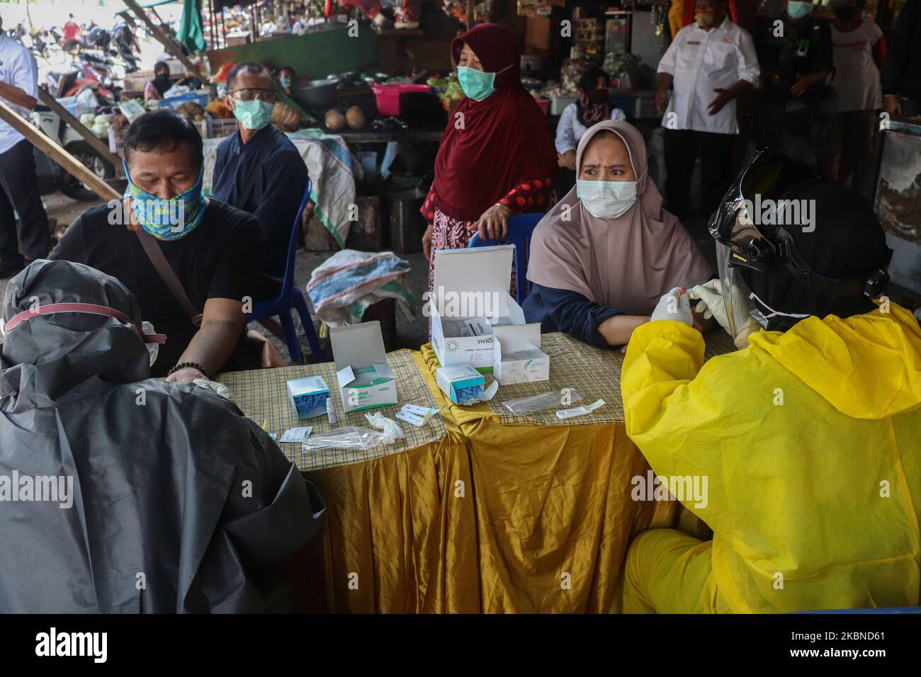 Medical personnel wearing personal protective equipment take blood samples during the Covid-19 rapid test to traditional market traders in Sidoarjo, East Java, on May 6, 2020. The Indonesian government continues to conduct a Covid-19 rapid test on residents to be immediately free of the Covid-19 pandemic. (Photo by Suryanto Putramudji/NurPhoto) Stock Photo