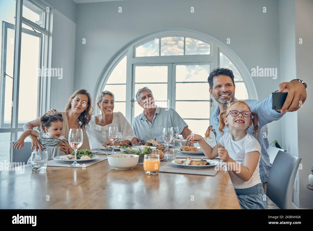 Grandparents, parents and children taking a selfie at dinner, eating