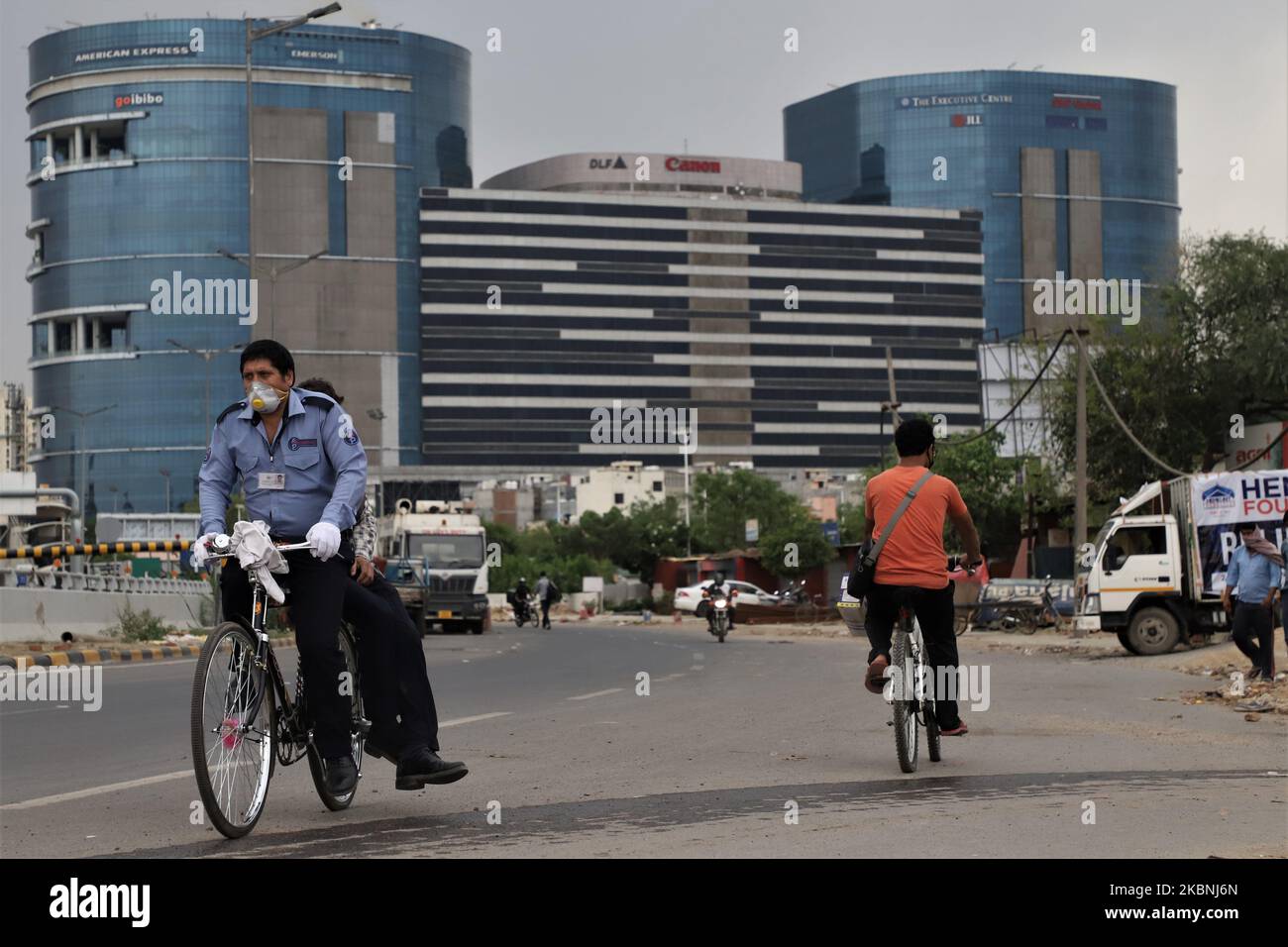 Cyclists wearing face masks move near DLF Building 5 amid COVID-19 coronavirus pandemic in Gurugram on the outskirts of New Delhi, India on 10 May 2020. DLF Cyber City houses some of the top IT and Fortune 500 companies. As one of the largest hives of IT activity in Delhi, it has been referred to as a â€œfuturistic commercial hubâ€. (Photo by Nasir Kachroo/NurPhoto) Stock Photo