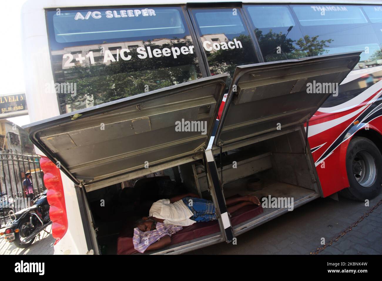 A man sleeps inside a luggage compartment of a tour bus in Mumbai