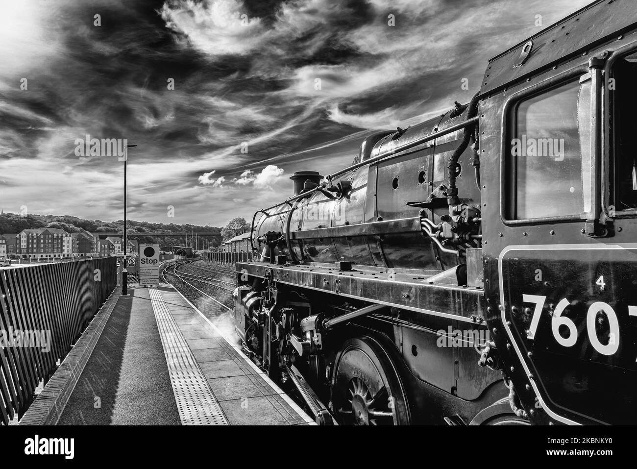 A polished black steam stands at a platform. Steam emits