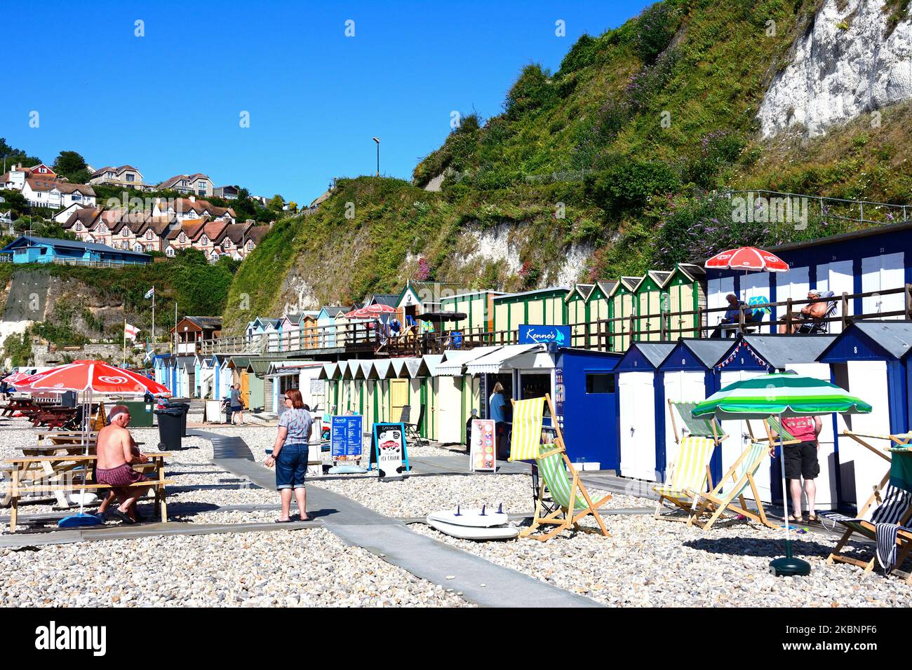 Cafe and beach huts on the beach with town buildings to the rear, Beer, Devon, UK, Europe. Stock Photo