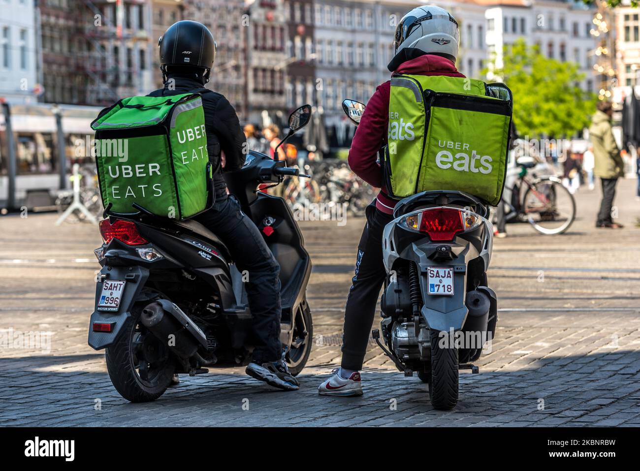 Two Uber Eats delivery courier wait outside Mc Donalds fast food in